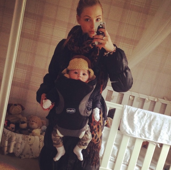 Posted on 5 January 2015, Caroline Thomas captures a candid mirror selfie at home while carrying her baby in a front sling, offering a cosy and unfiltered glimpse into early motherhood, complete with soft nursery details and a quiet, intimate atmosphere. | Source: Instagram/carolinethomas23