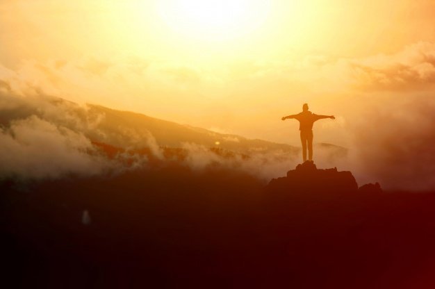 The silhouette of a man on top of a mountain. | Source: Freepik