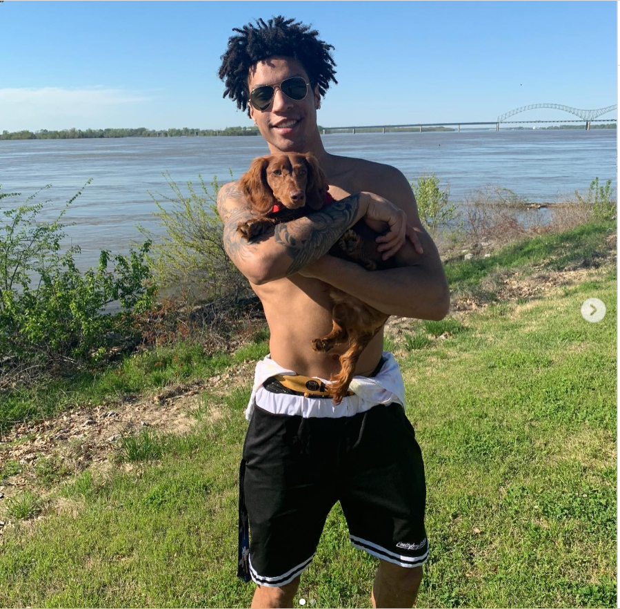 Brandon Clarke holds a brown dachshund while posing shirtless near the waterfront on a sunny daYy | Source: Instagram/brandon_clarke23