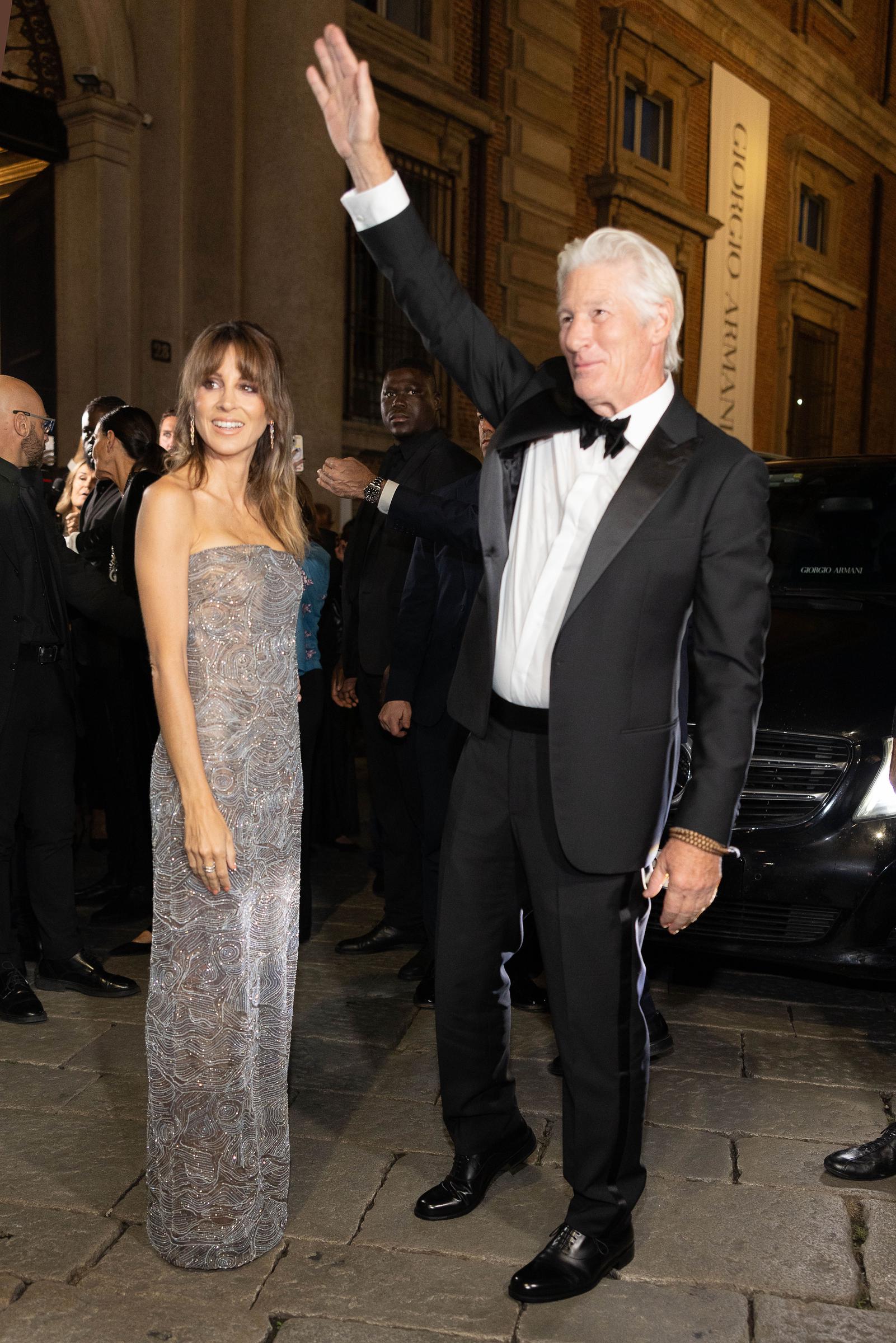 Richard Gere salutes the crowd with a raised arm as Alejandra Silva dazzles at his side, commanding attention in a shimmering gown that captured the evening’s tone.