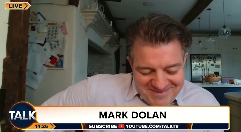 Captured mid-interview, Liam Halligan reacted with a modest smile and a slight downward glance as he addressed questions about his relationship with Kate Garraway, offering a candid and humanising moment amid an otherwise policy-focused broadcast. | Source: YouTube/TalkTV