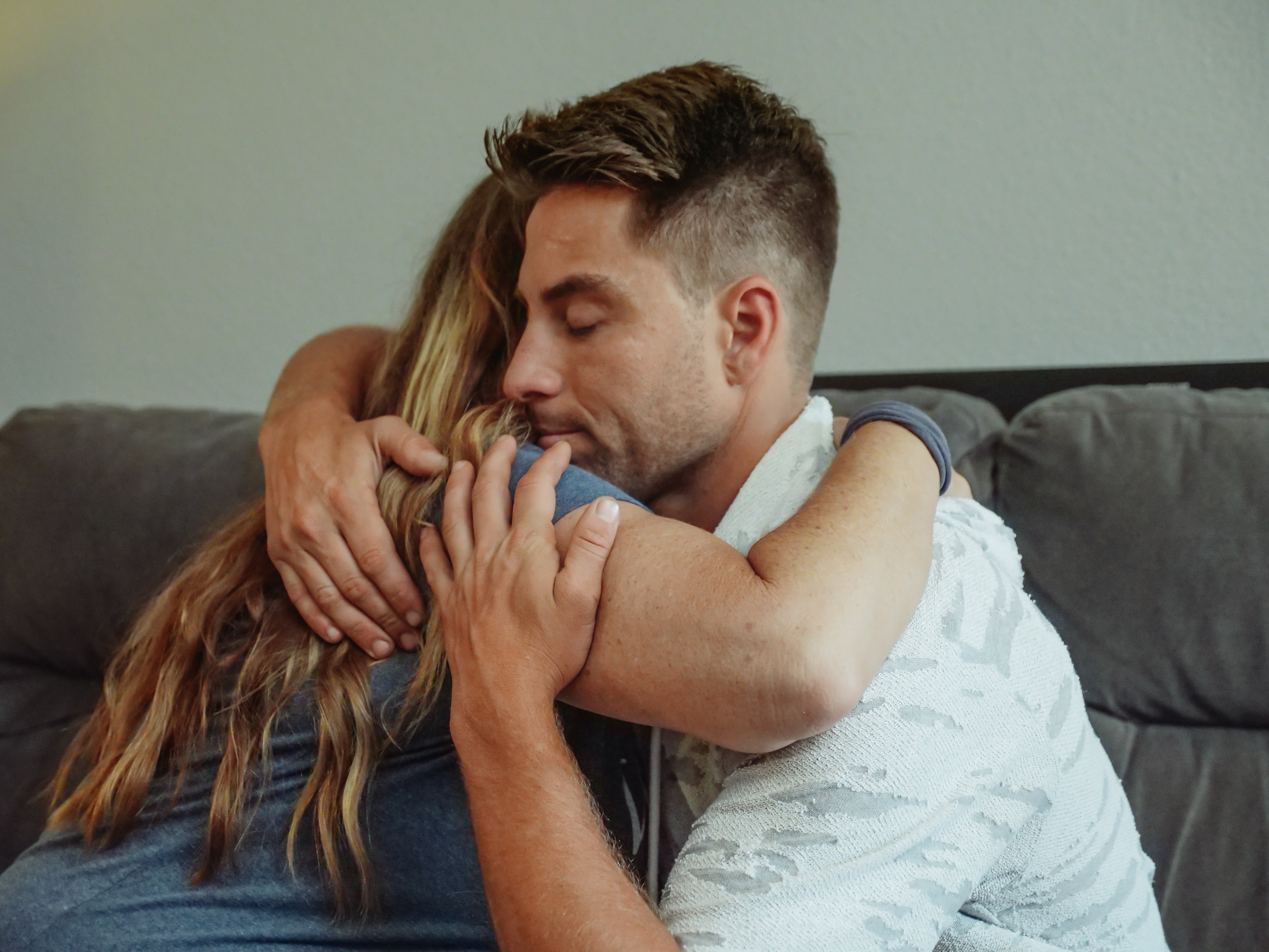 Un hombre abrazando a una mujer sentados en un sofá. | Foto: Pexels