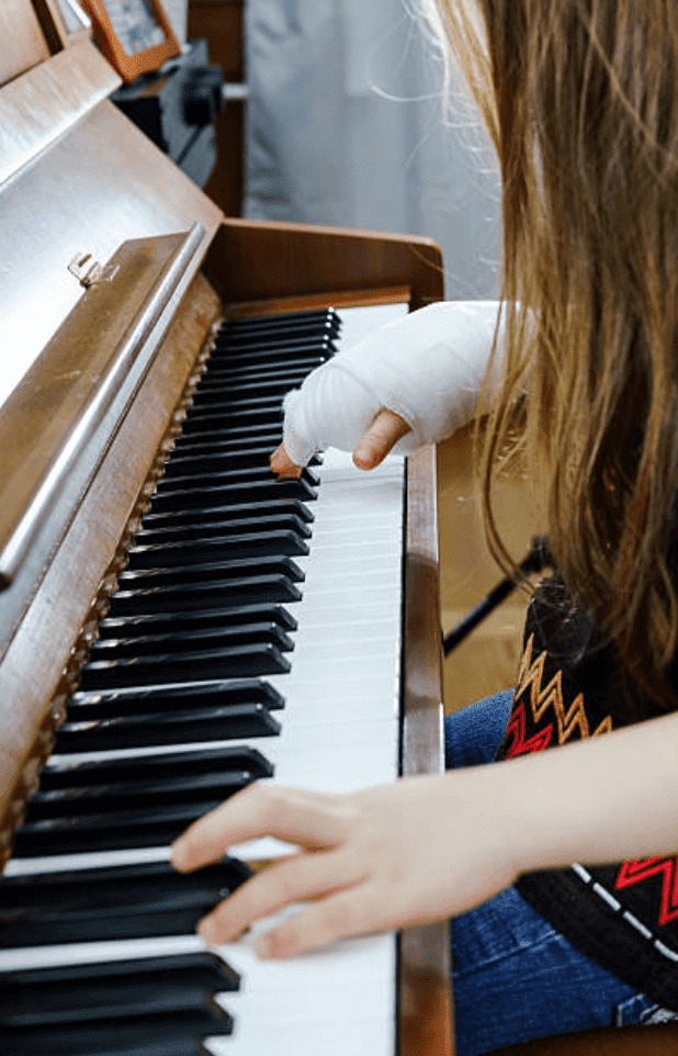 Child plays piano with bandaged hand | Source: Getty Images