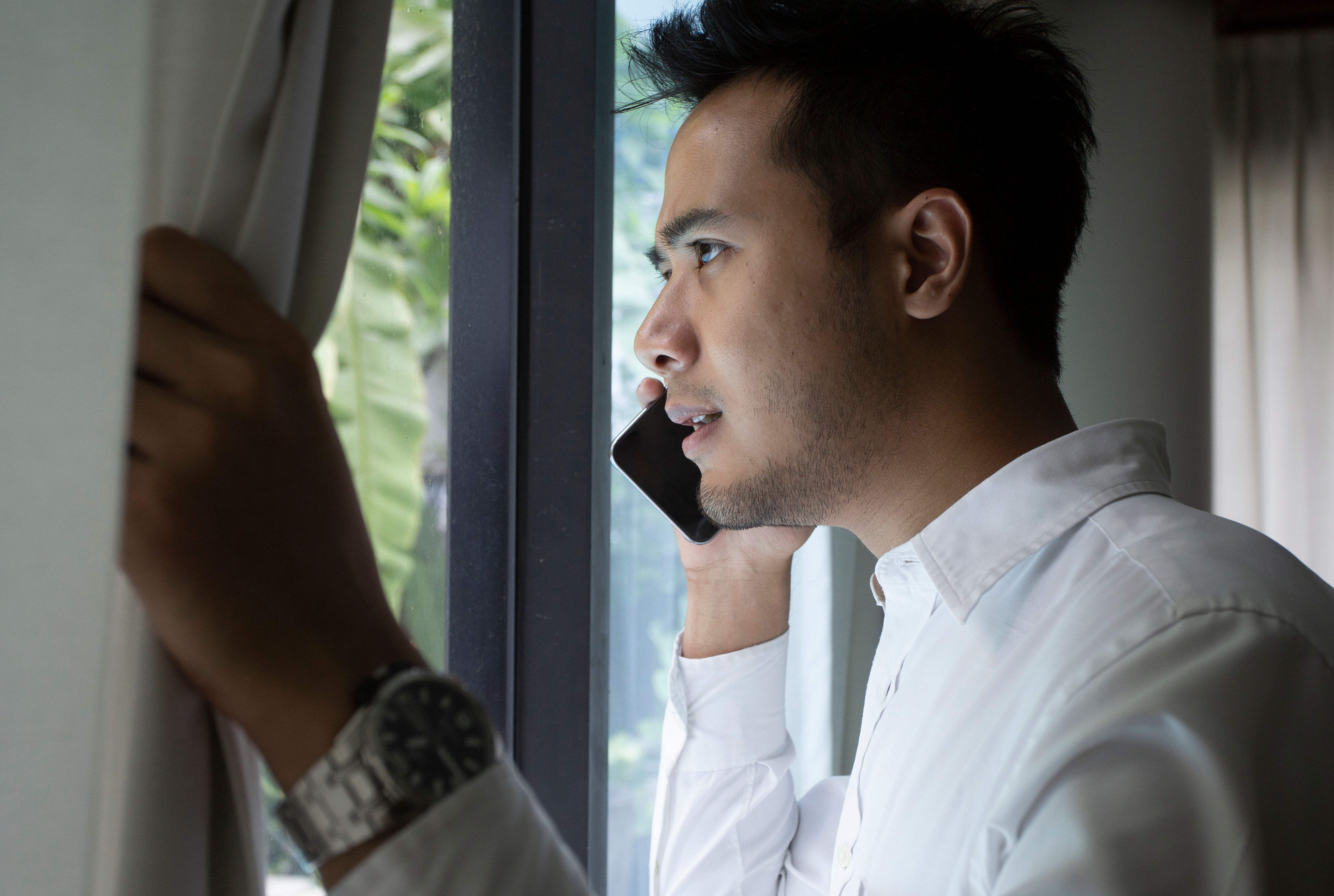 Man is talking on the phone near the window | Source: Shutterstock.com