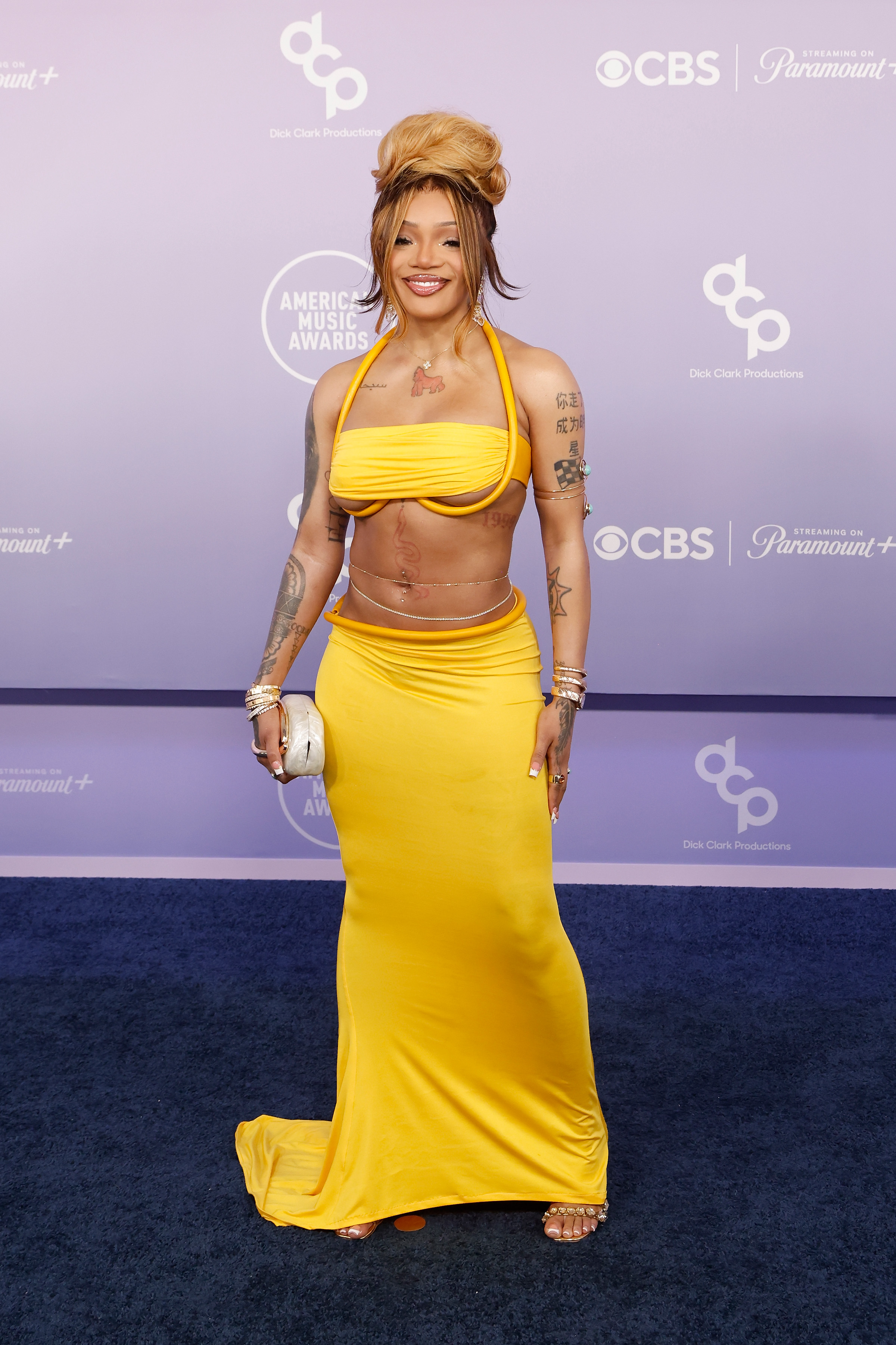 GloRilla smiles on the carpet in a vibrant yellow look with matching heels and statement jewelry | Source: Getty Images
