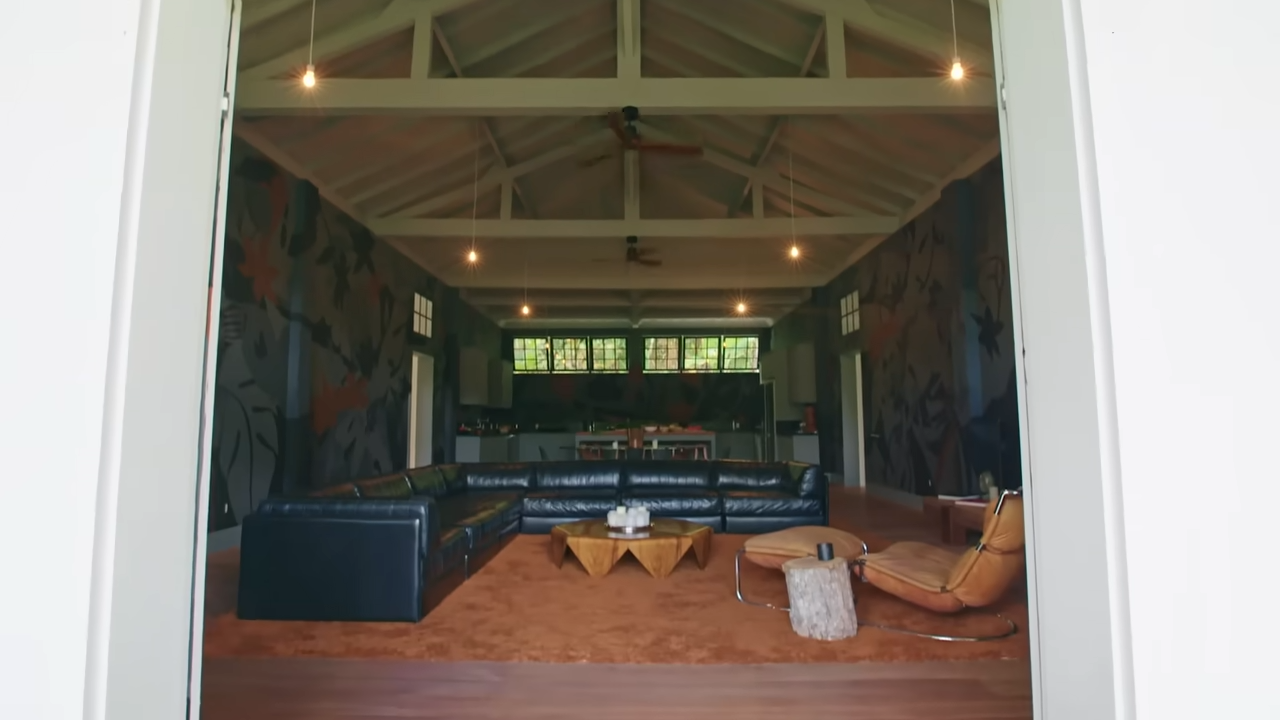 The sprawling guest house functions as a massive, open loft-style layout featuring double wings, four bedrooms, and customized moody tropical murals. | Source: YouTube/@Archdigest