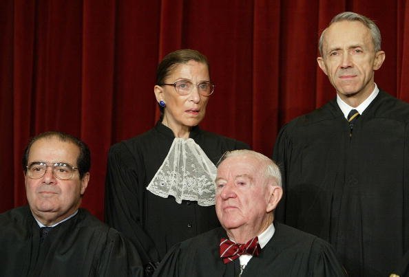  US Supreme Court Justices (L-R, Seated) Associate Justice Antonin Scalia and Associate Justice John Paul Stevens, (L-R, Standing) Associate Justice Ruth Bader Ginsburg and Associate Justice David H. Souter pose for pictures at the US Supreme Court December 5, 2003, in Washington, DC. | Source: Getty Images.