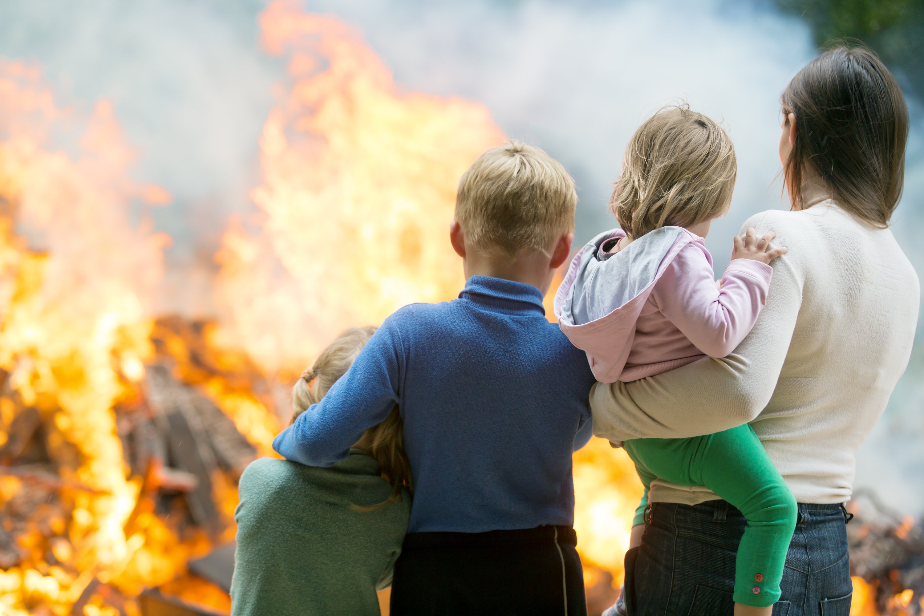 Family standing outside burning home. Image credit: Shutterstock