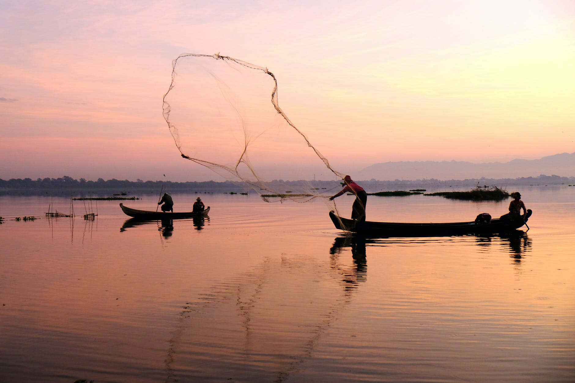 Un par de pescadores lanzando las redes en un lago. | Foto: Pexels