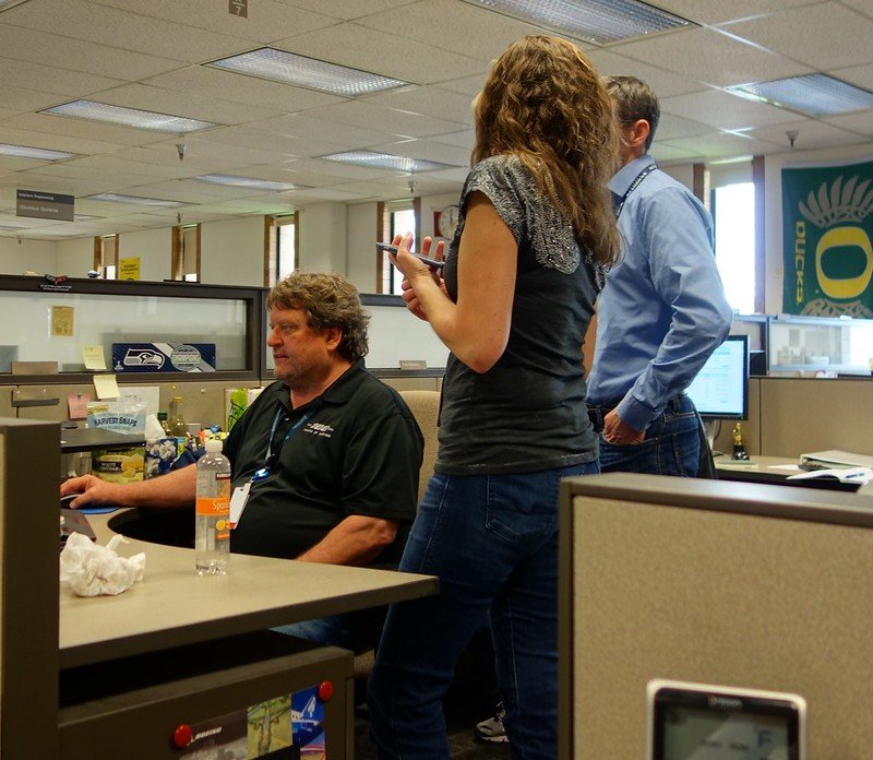 A couple talking to a Man at his desk. | Photo : Flickr