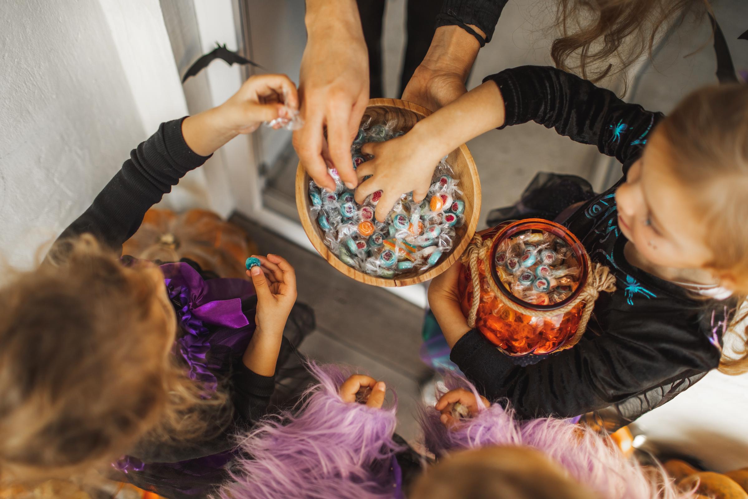Two kids grabbing candy while trick-or-treating | Source: Getty Images