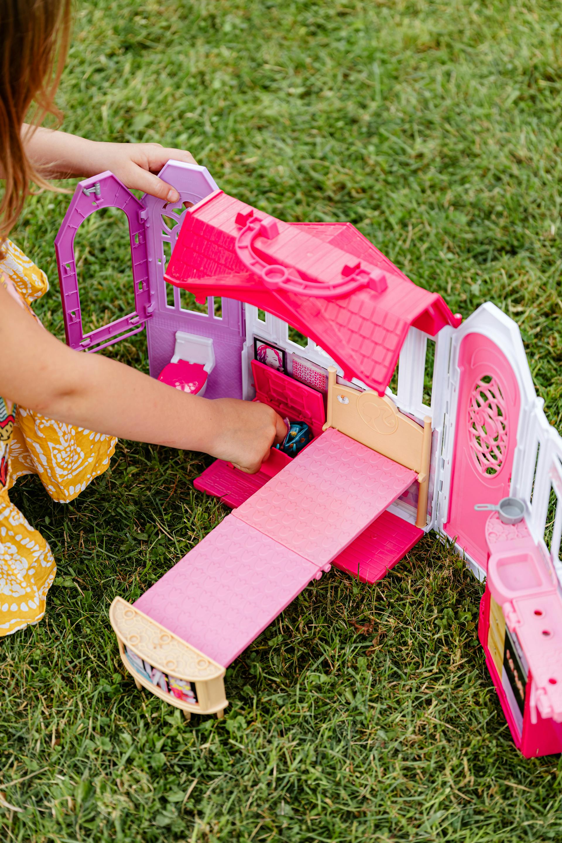 A little girl playing with a toy house | Source: Pexels