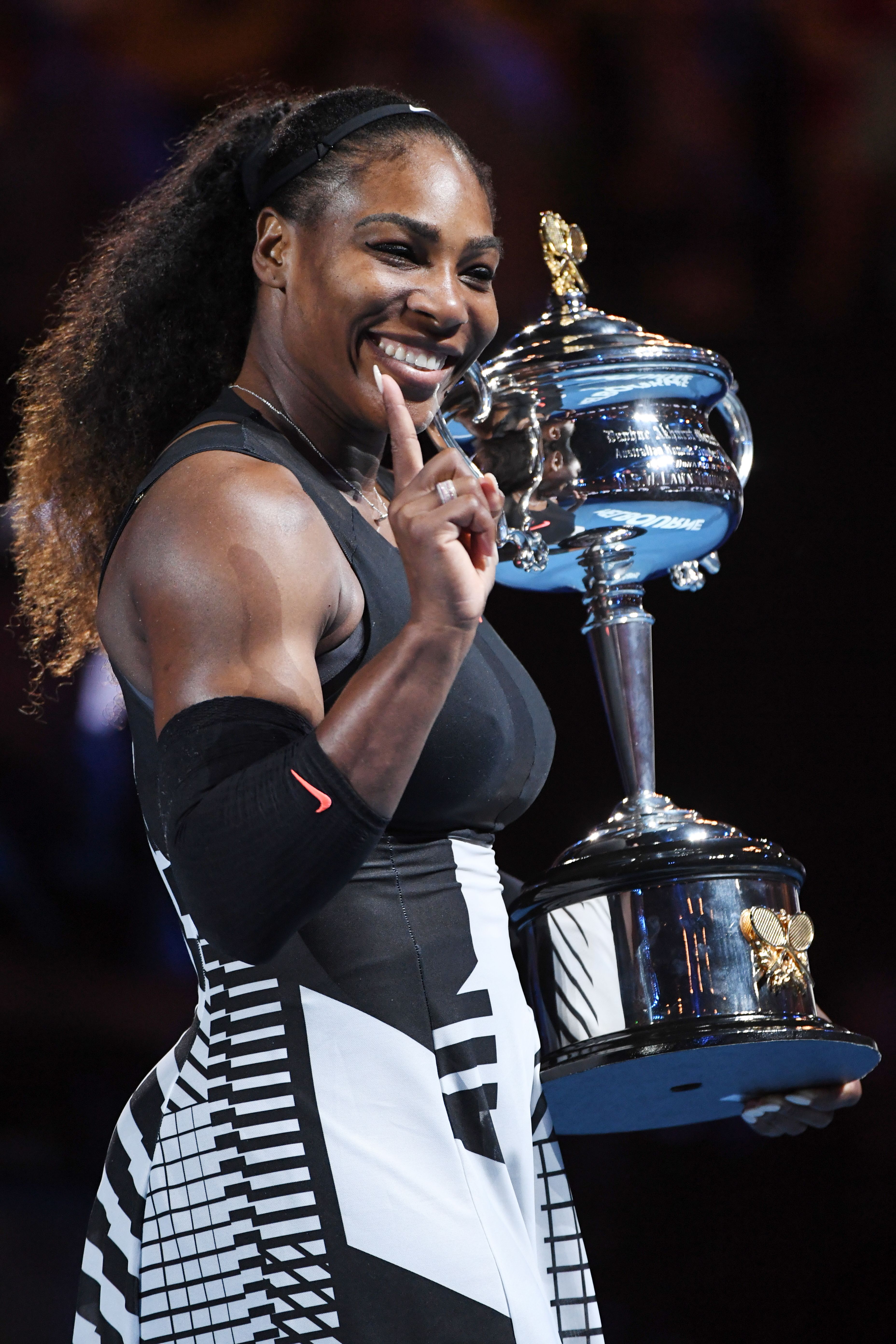 Serena Williams held up the championship trophy after winning the Australian Open in January 2017. She wore a black and white Nike outfit and smiled brightly as she posed for photos on the court.