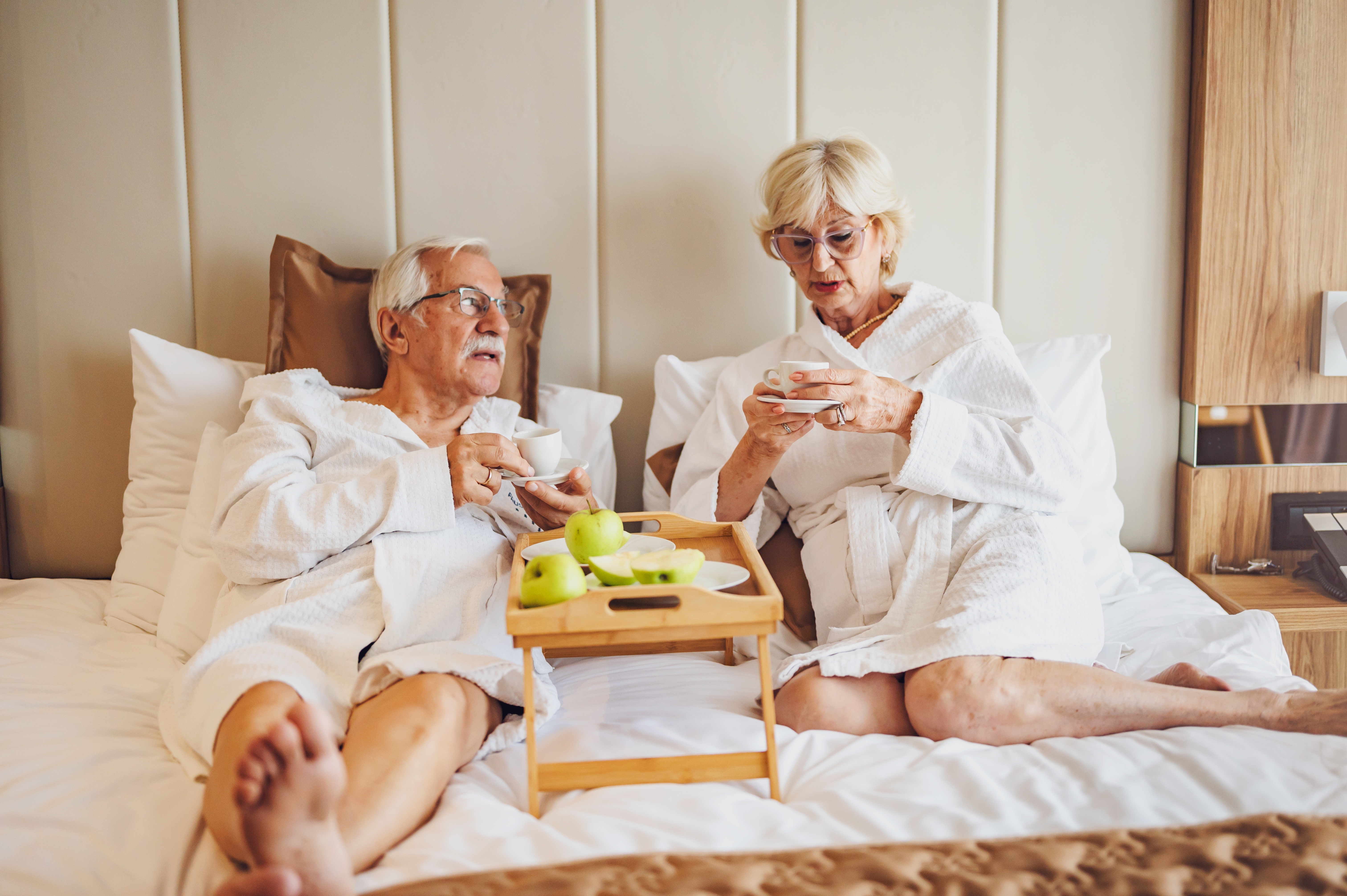 An elderly couple drinking coffee in a hotel room | Source: Shutterstock