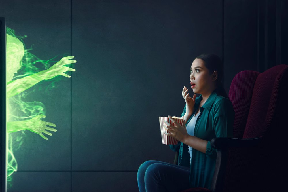 Shocked woman watching tv with popcorn in hand | Photo: Shutterstock