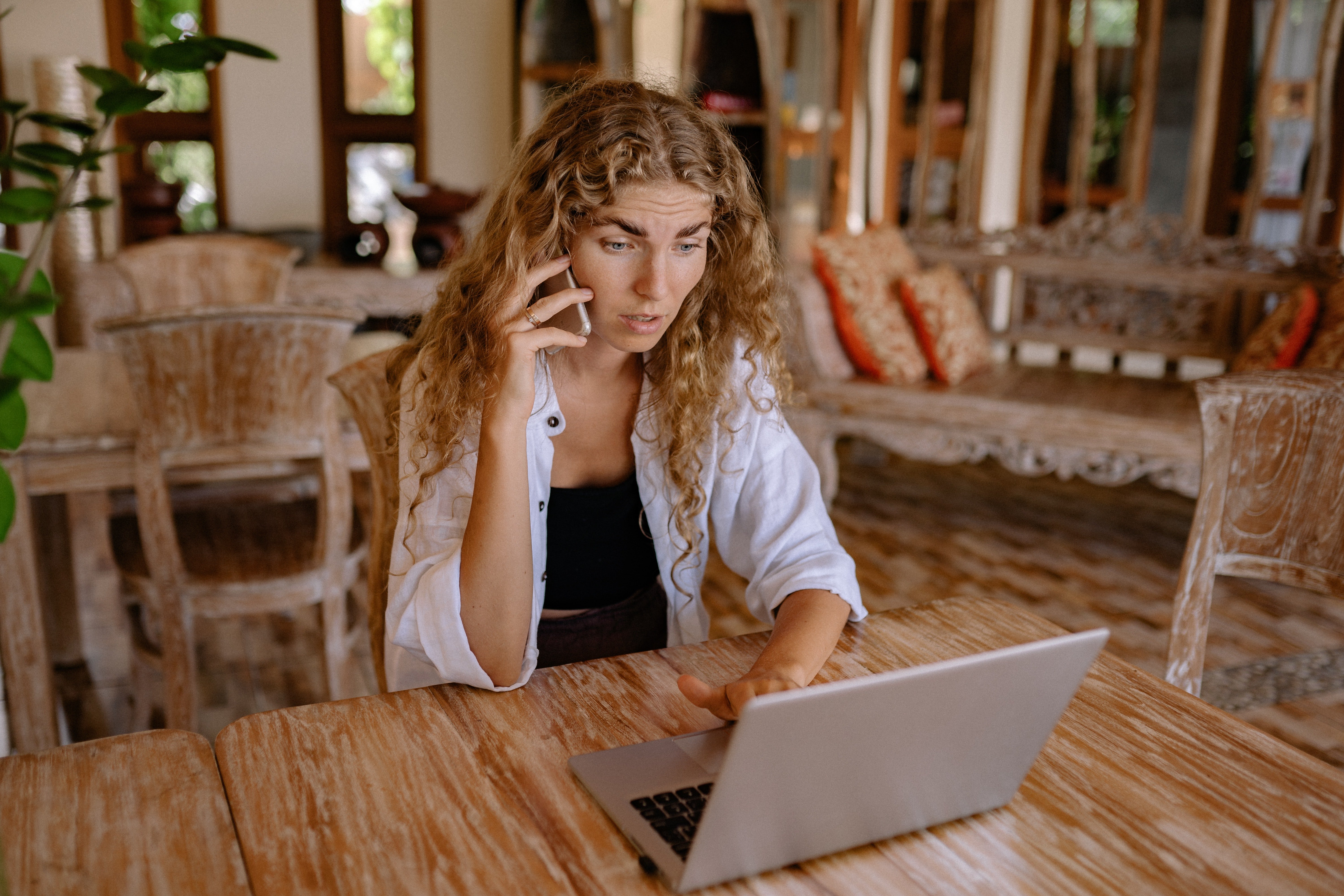 Woman looking at a laptop while using a phone | Photo: Pexels