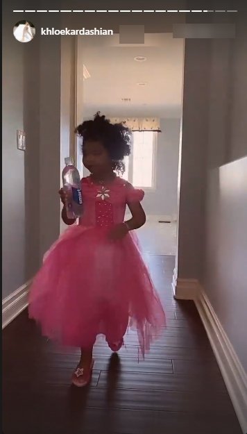 Khloe Kardashian’s daughter True holding a water bottle while wearing a pink dress. | Source: Instagram/khloekardashian 