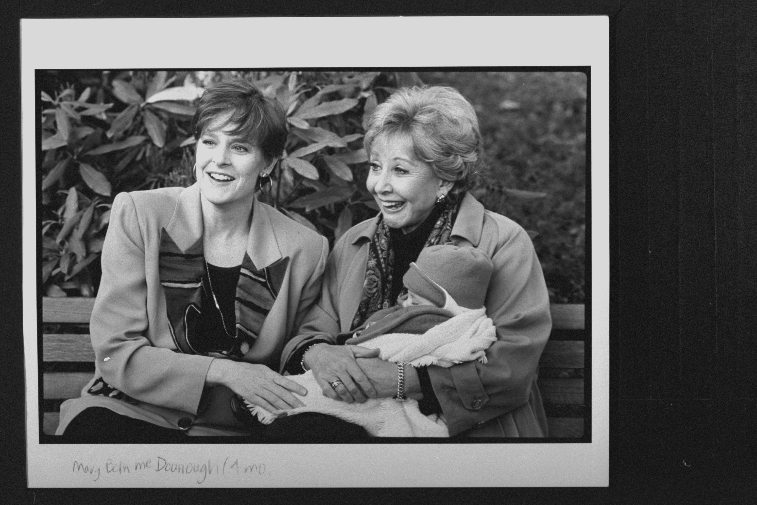 Former cast members of the TV show "The Waltons" Mary McDonough and Michael Learned sitting on bench as as Learned holds McDonough's 4-mo-old baby, Sydnee Wickstrom at the opening of the Walton Mountain Museum | Source: Getty Images