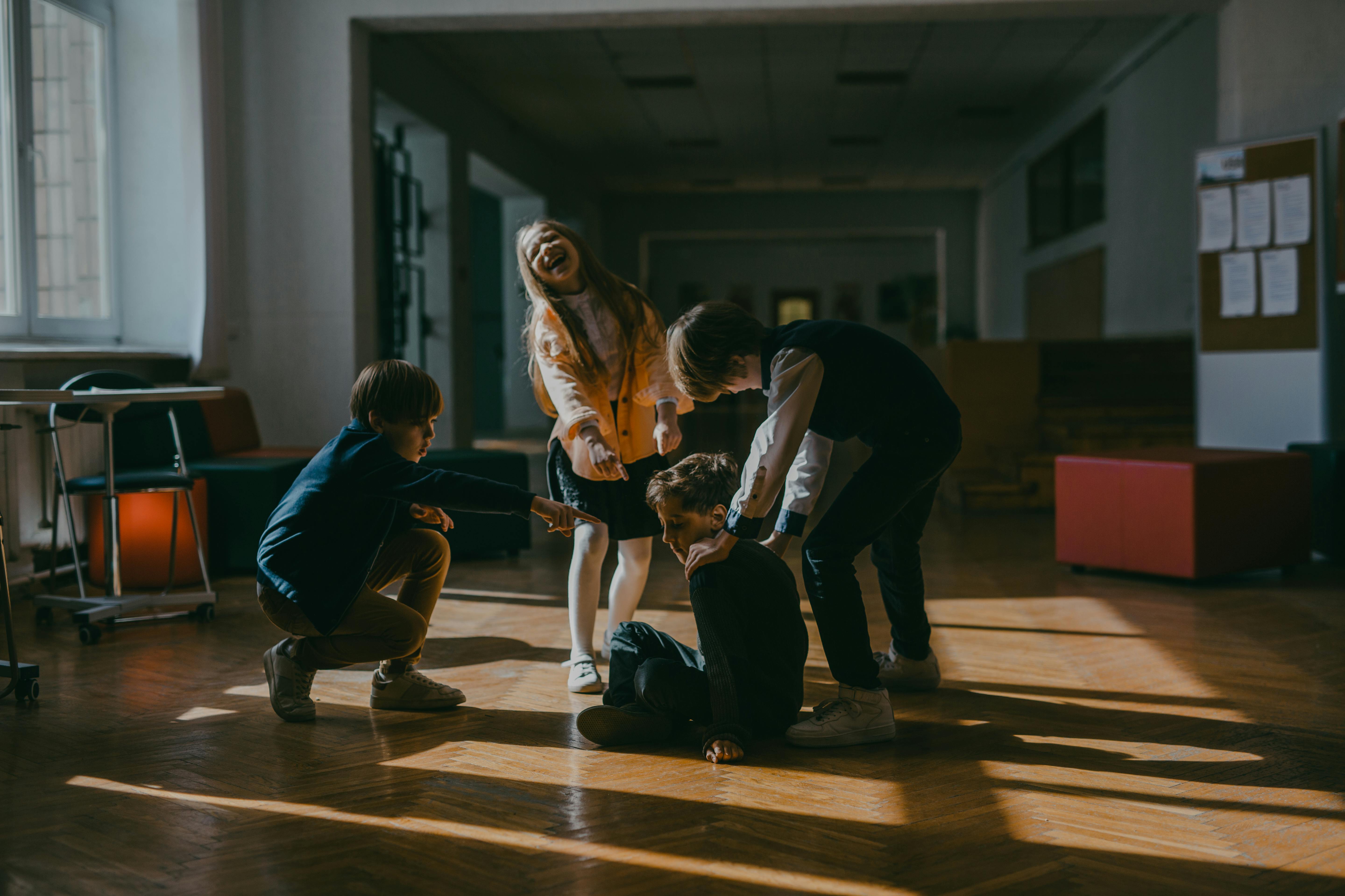 A group of children point and laugh at a seated classmate, capturing a moment of peer intimidation in a school setting. | Source: Pexels