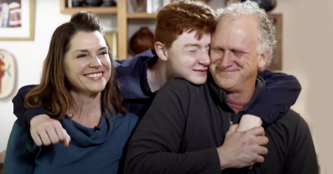 A teen embraces his adoptive parents. | Source: youtube.com/BoysandGirlsAid