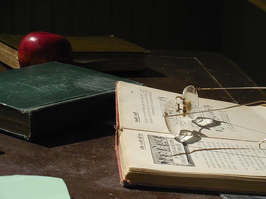Teacher's spectacles, books, and an apple on a table | Photo: Pickist