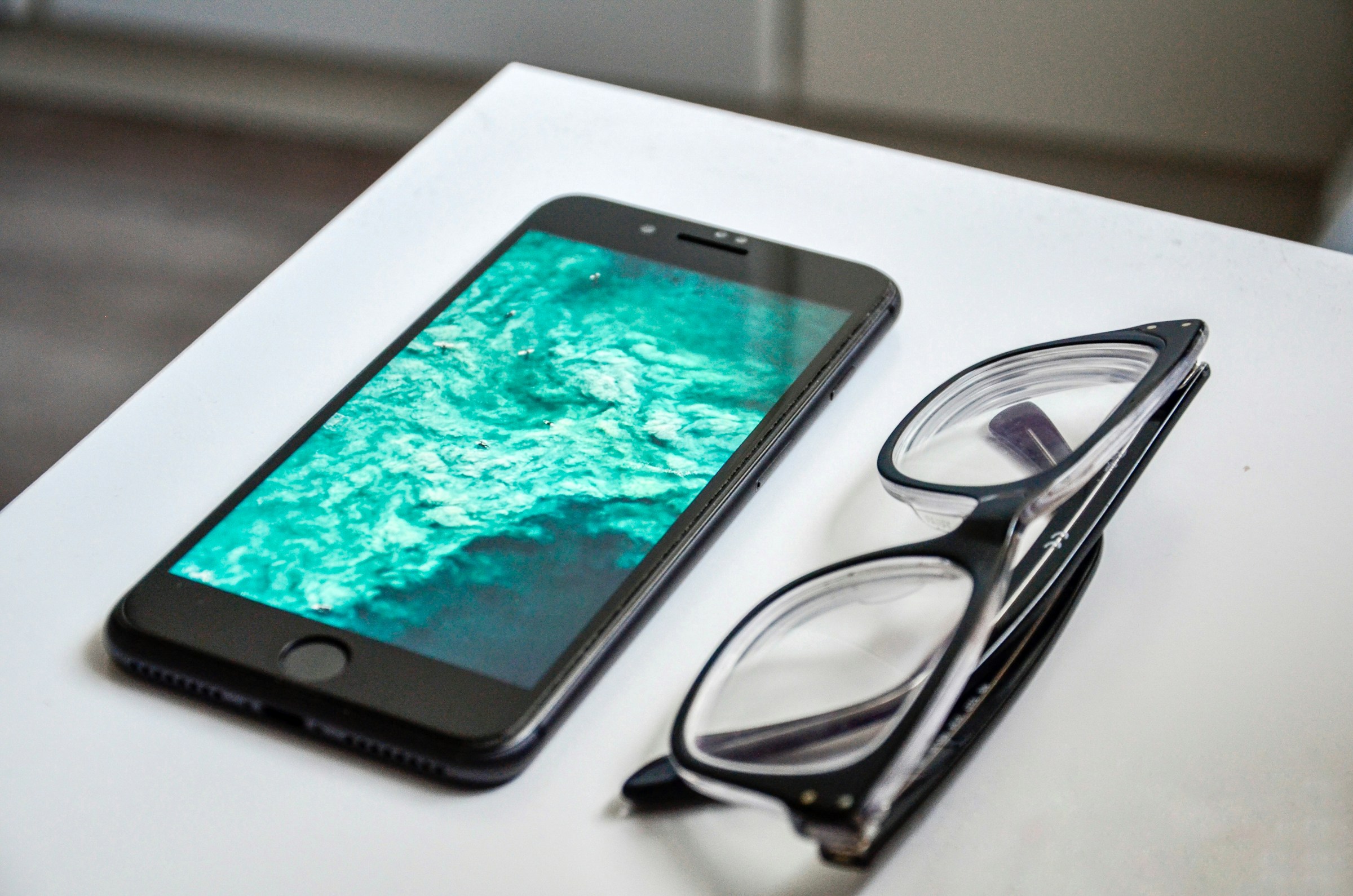 A smartphone and a pair of glasses lying on a table | Source: Unsplash