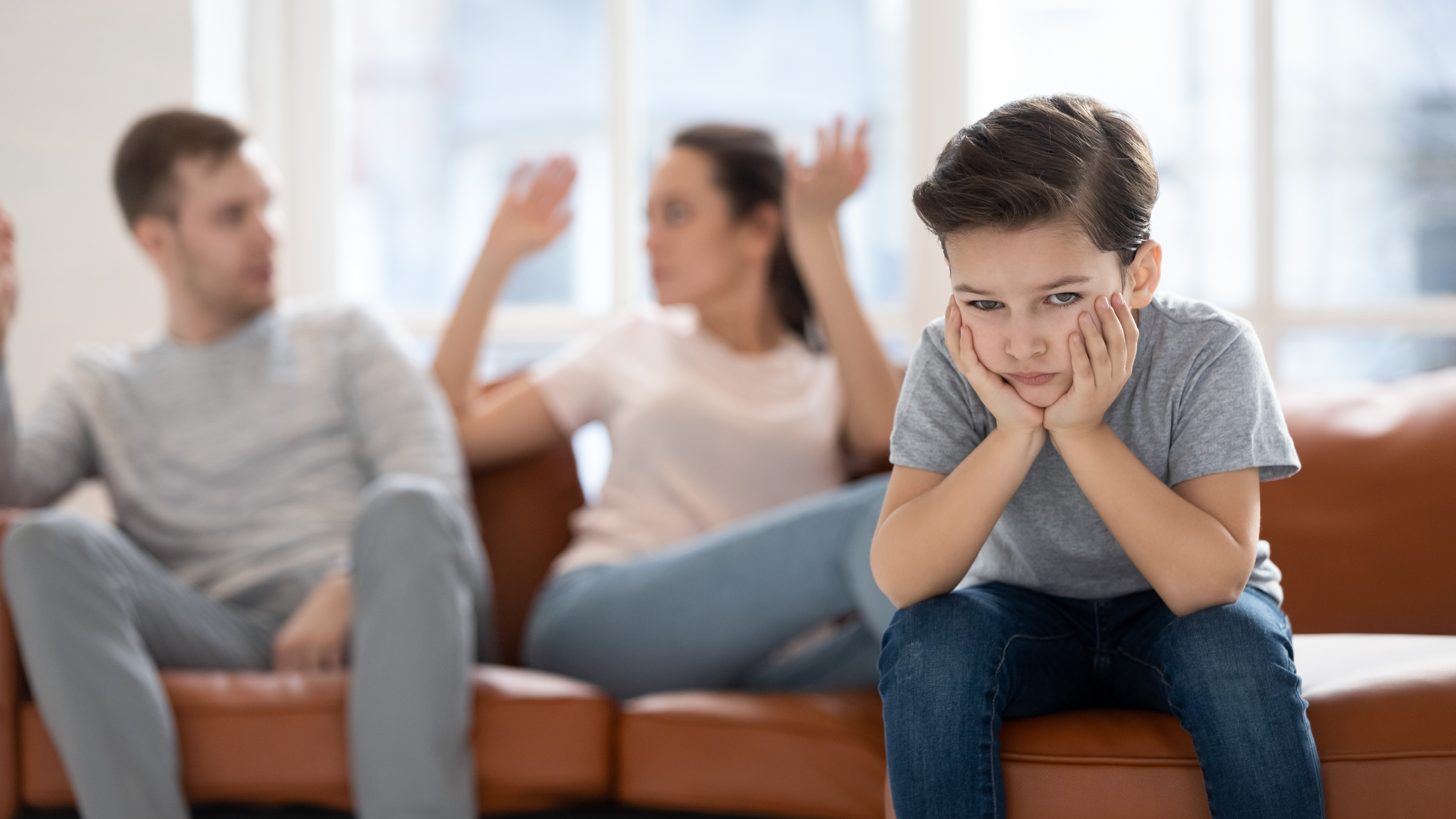 A child sulking while a couple argues behind him | Source: Shutterstock