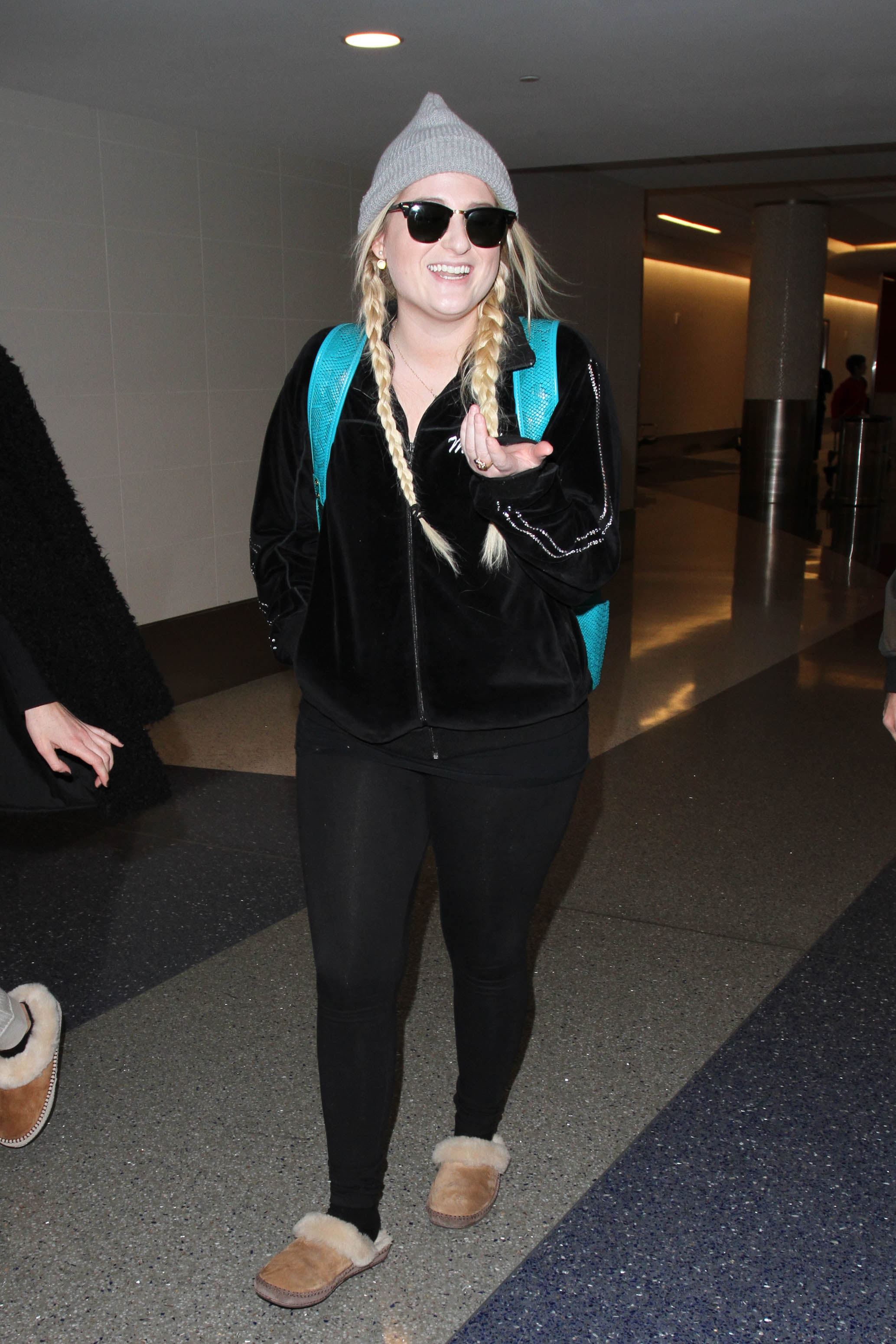 Meghan Trainor is spotted at LAX in Los Angeles sporting a laid-back travel look, complete with braids, a cozy beanie, and oversized sunglasses. Dressed in all black with shearling slippers and a teal backpack, she pulls off an effortless, airport-chic vibe.