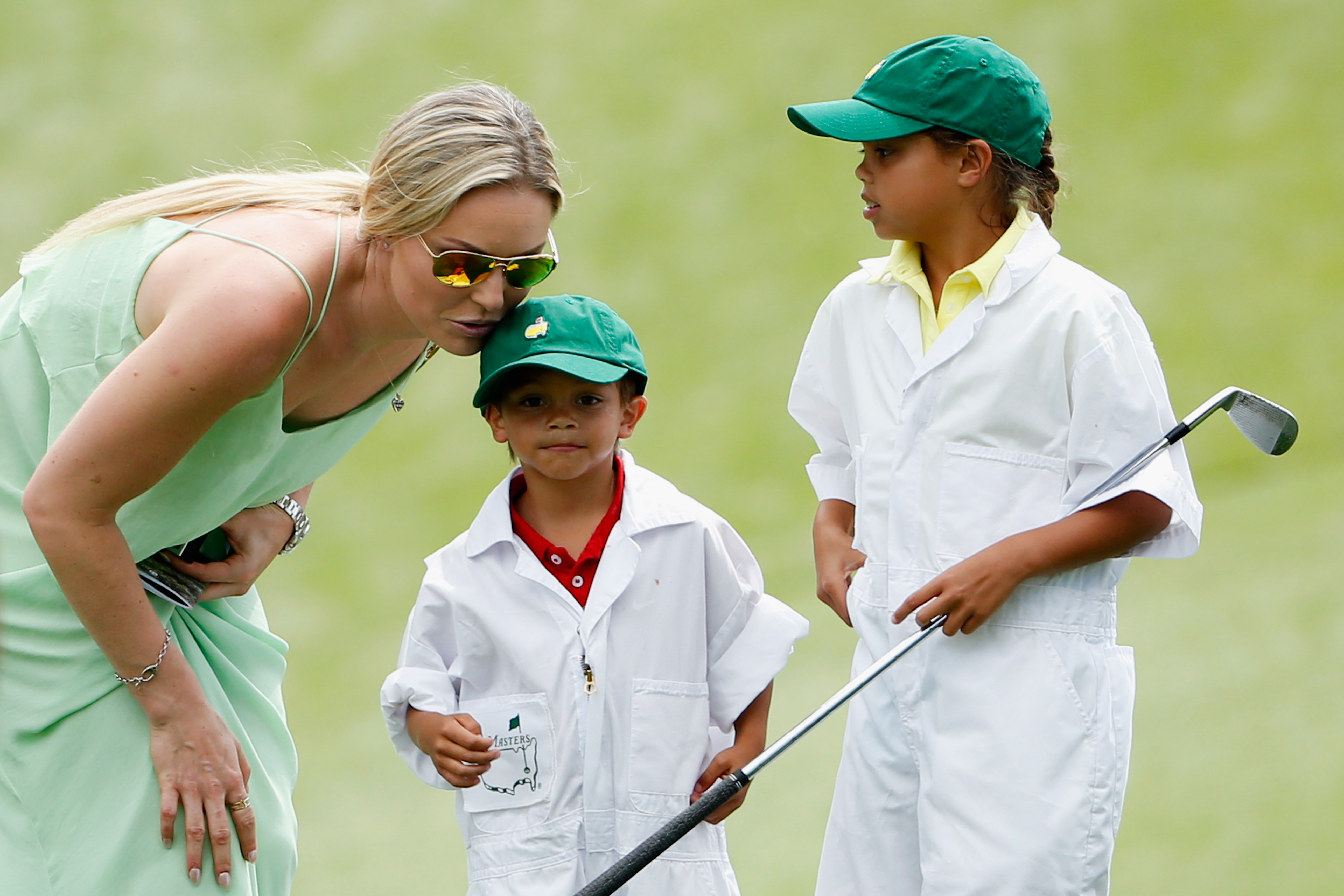 Lindsey Vonn leaning down to interact with Charlie and Sam Woods at the Par 3 Contest prior to the start of the 2015 Masters Tournament. | Source: Getty Images