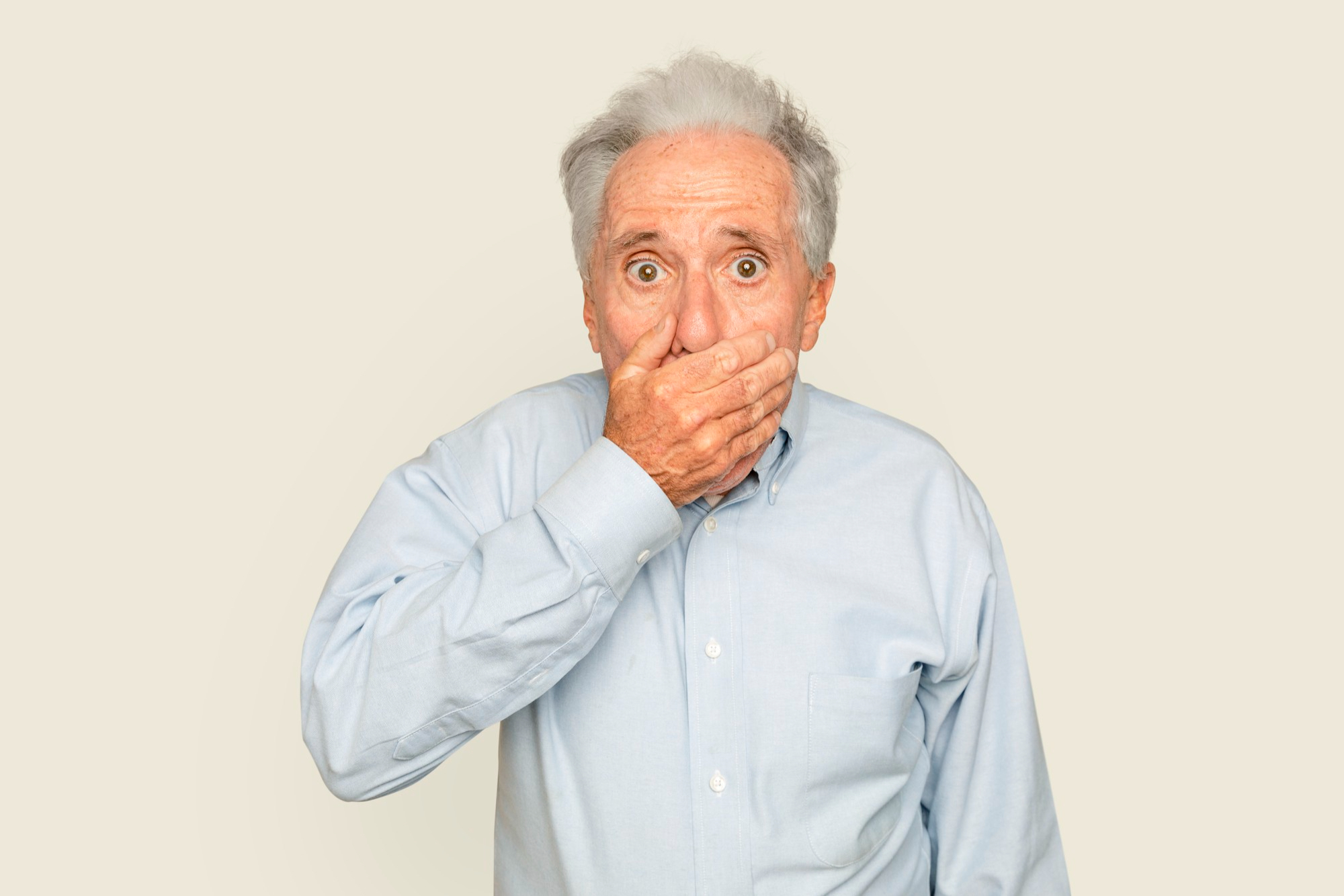 An older man covering his mouth in shock | Source: Freepik