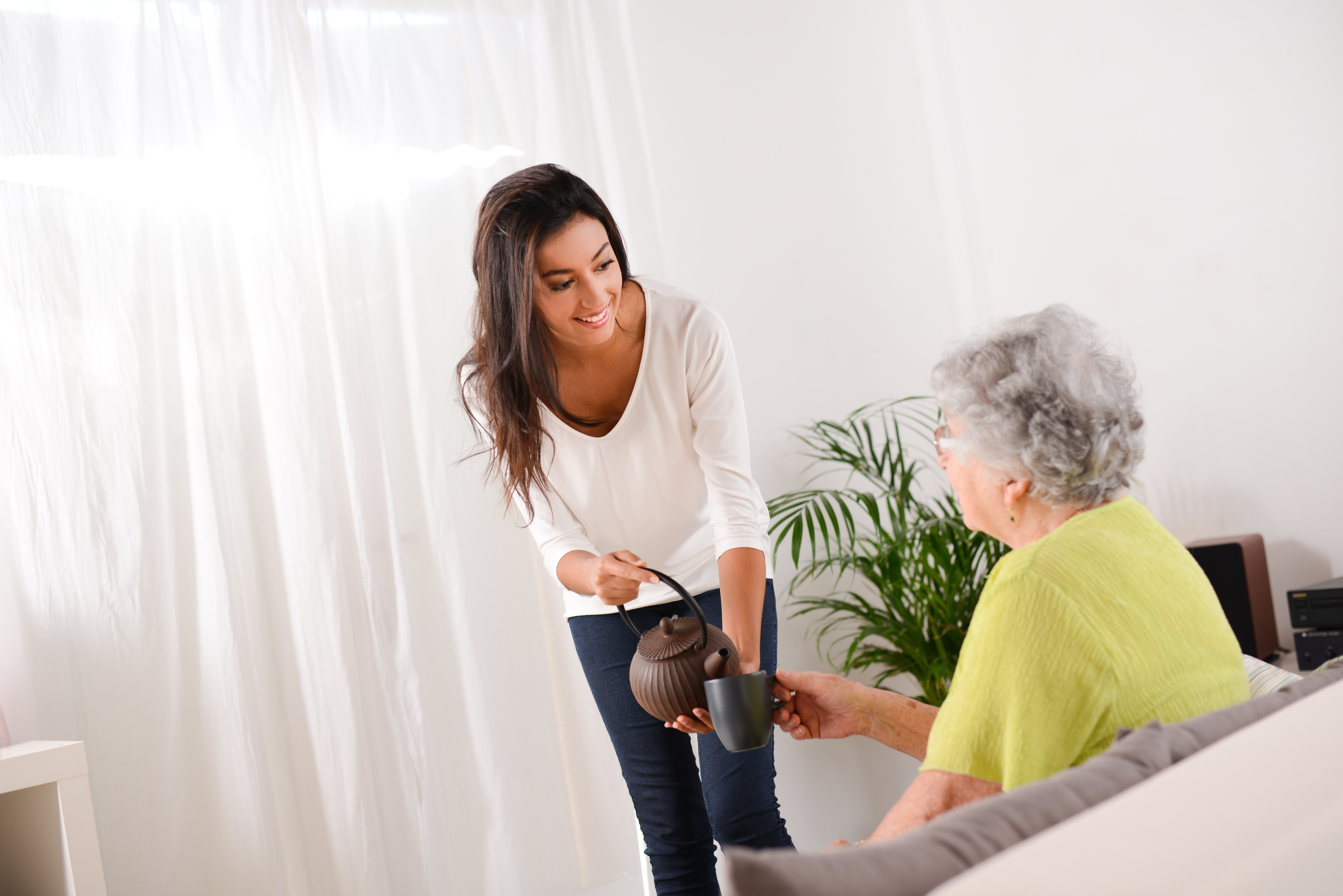 A woman bringing an elderly woman tea | Source: Shutterstock