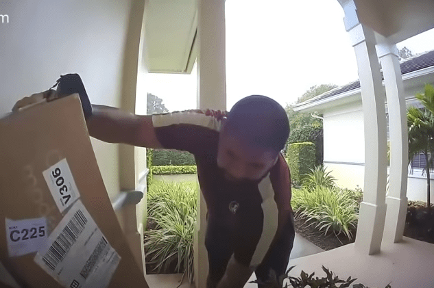 The USPS delivery worker stacking the FedEx packages in the corner | Photo: Youtube.com/Gabe White