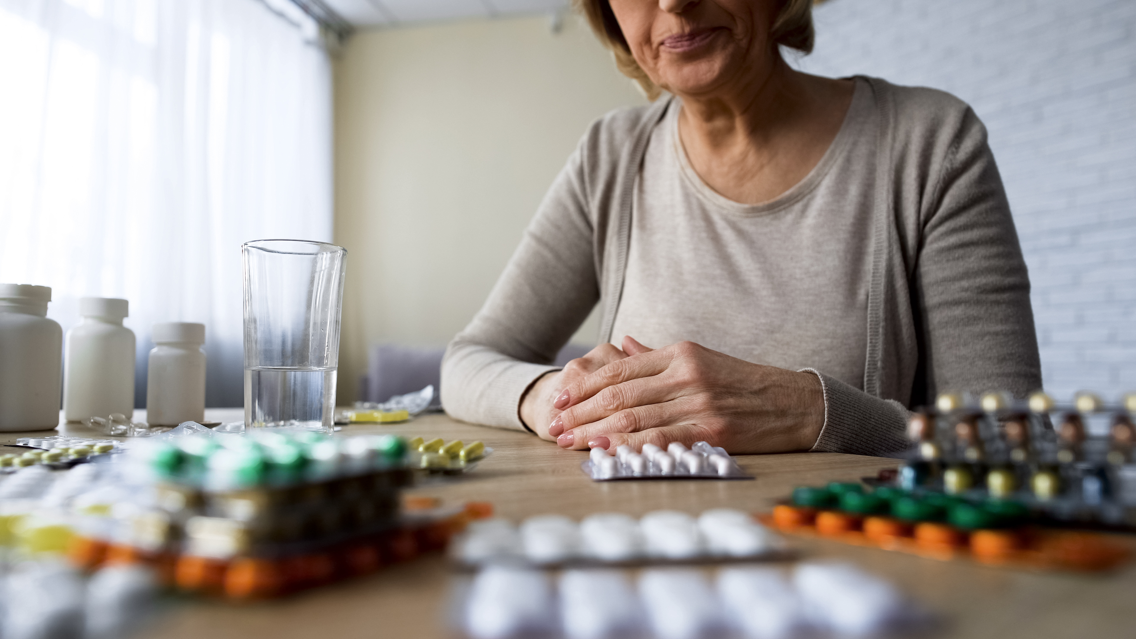 Woman with an excess amount of vitamins and supplements on a table | Source: Shutterstock