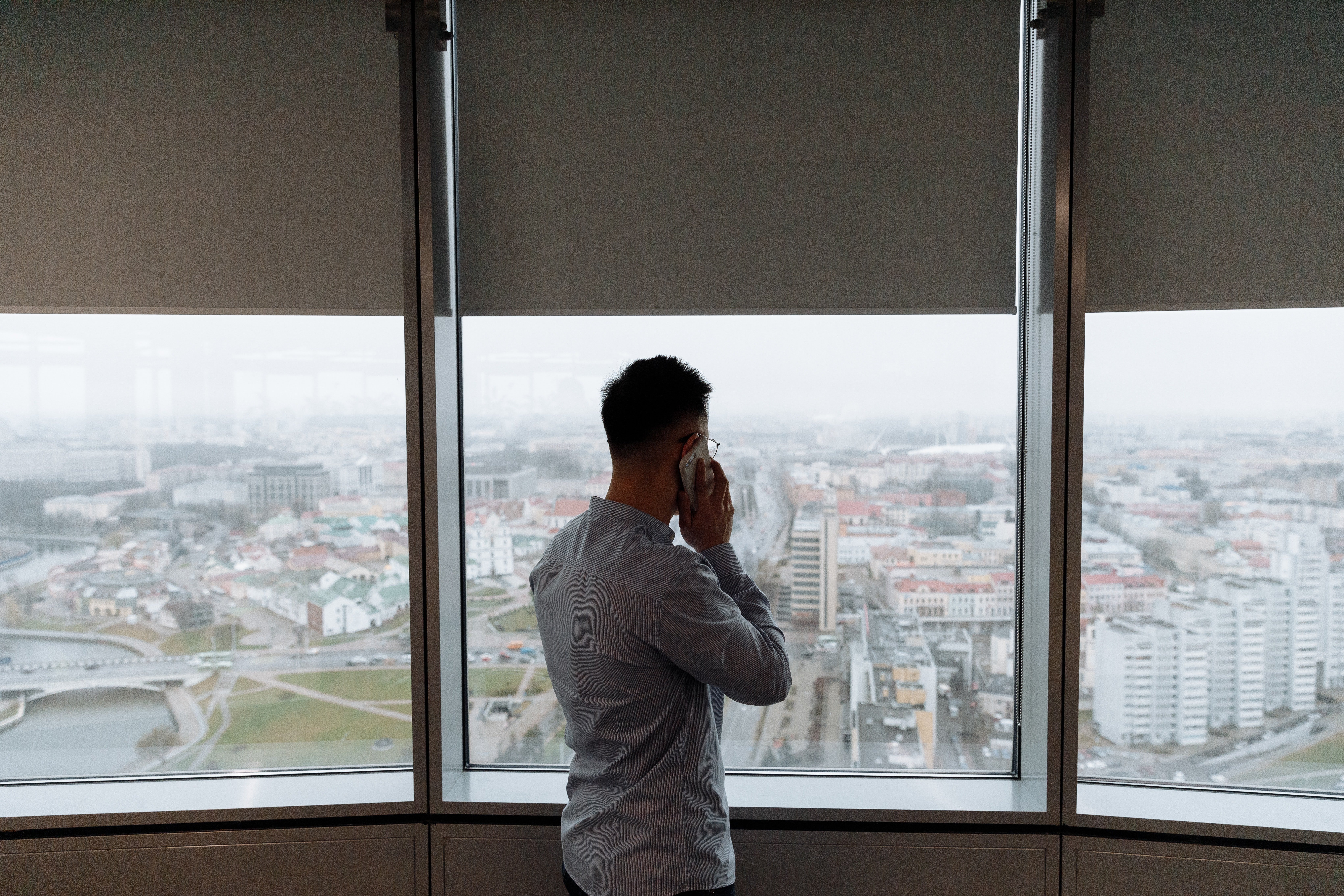Hombre hablando por teléfono celular mientras mira por un ventanal. | Foto: Pexels