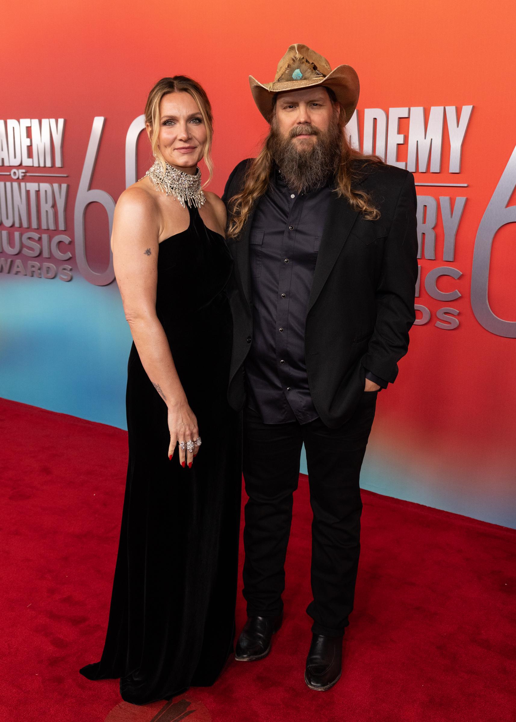Morgane and Chris Stapleton appear at the 60th ACM Awards held at the Ford Center. Chris keeps it classic with a black suit and cowboy hat, while Morgane shines in a velvet halter gown and silver jewelry as they walk the carpet.