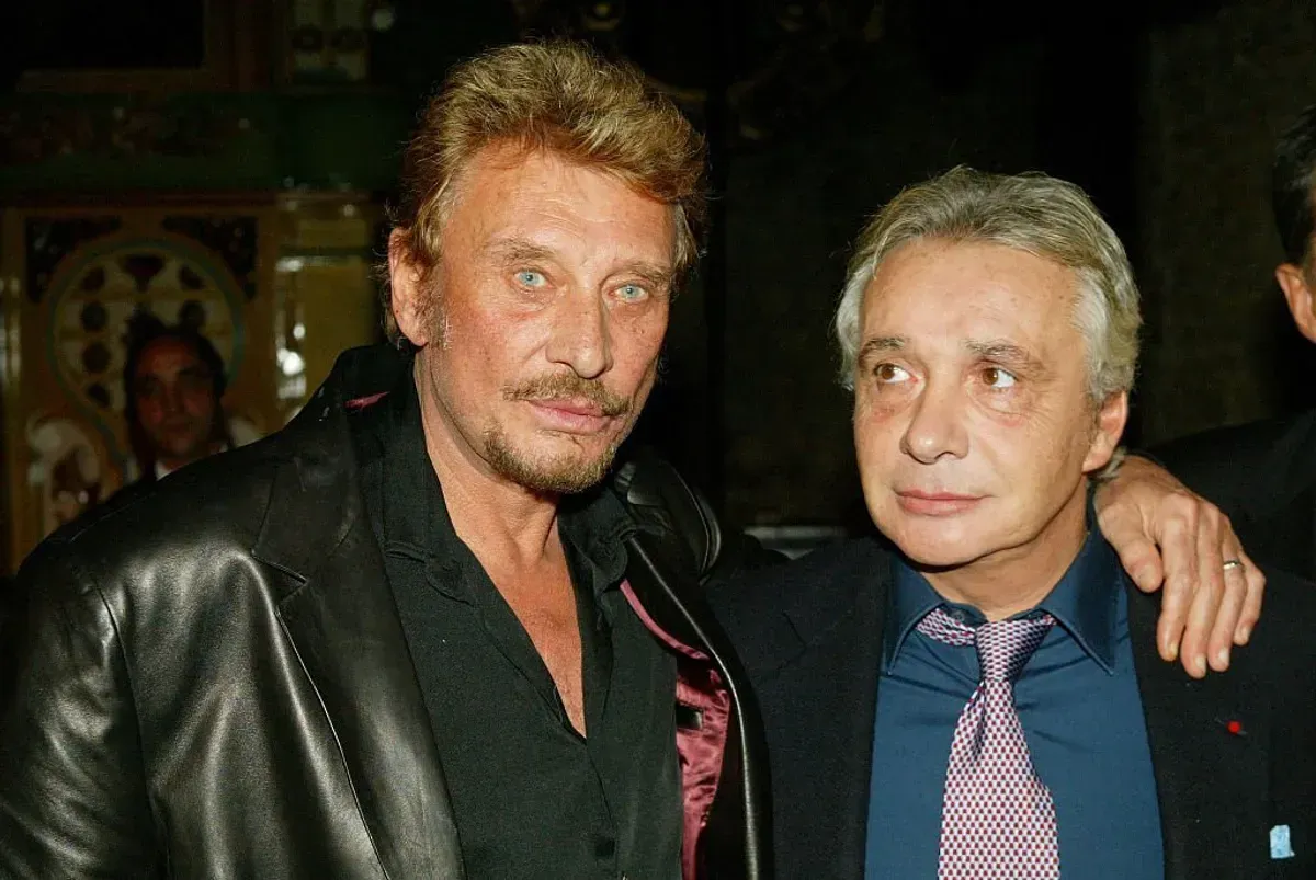 Johnny Hallyday (L) et Michel Sardou assistent à la cérémonie où le producteur et directeur artistique français, Jean-Claude Camus, a reçu la croix "Arts et lettres". | Photo : Getty Images