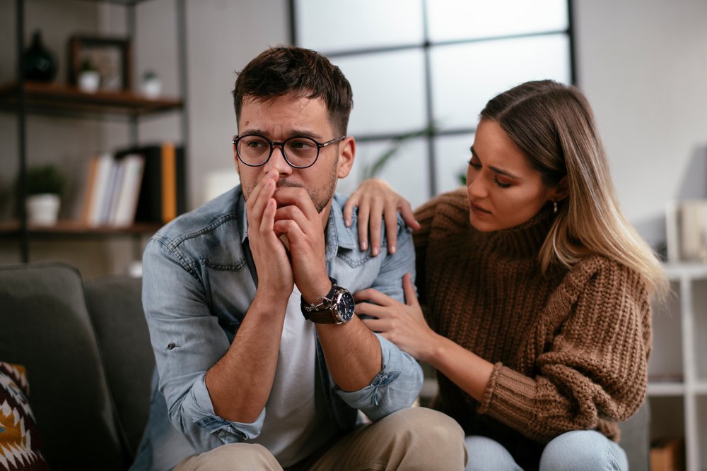 Pareja con cara de angustia sentada en un sofá. | Foto: Shutterstock