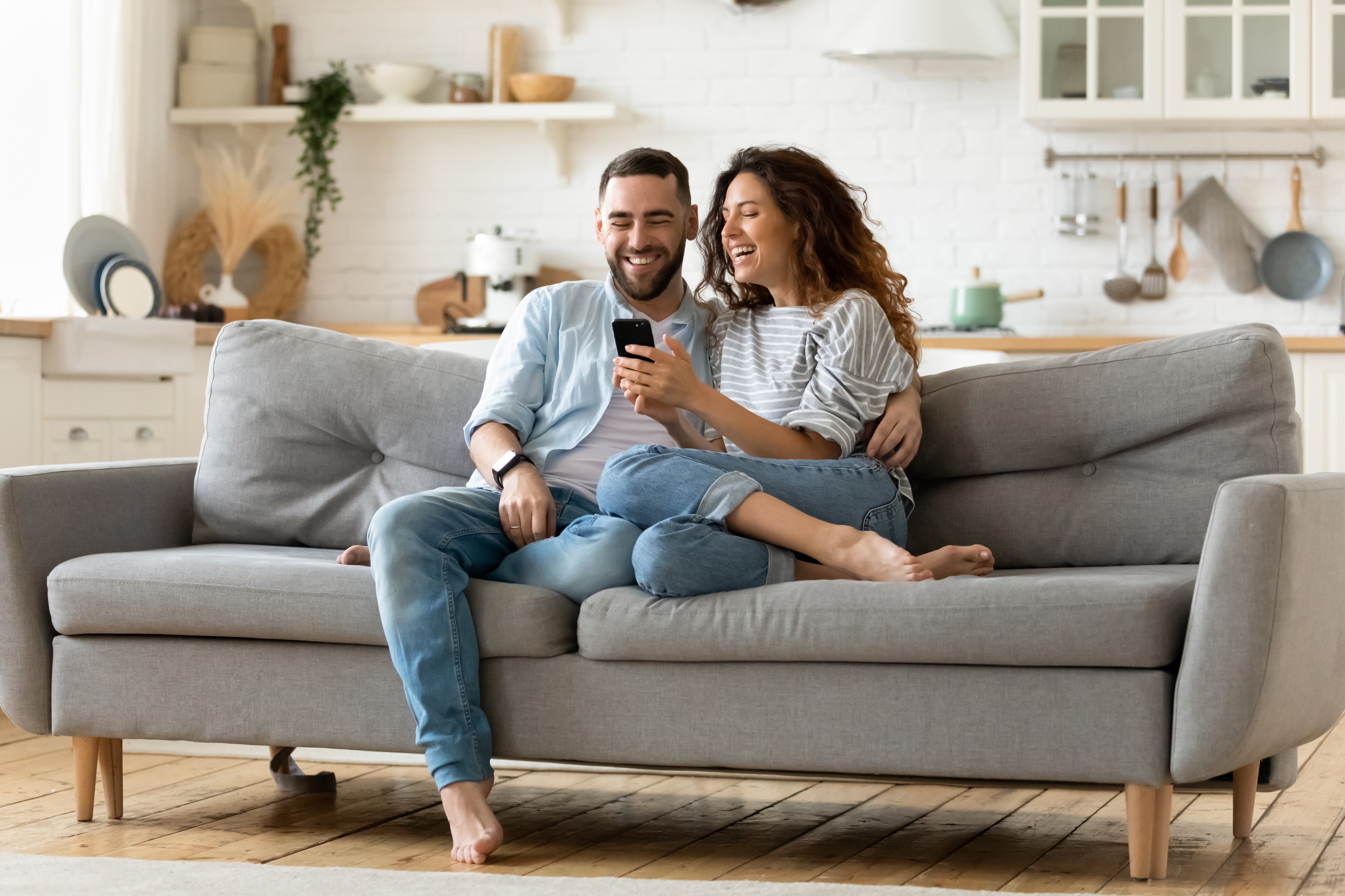 A happy couple sitting on a couch | Source: Shutterstock