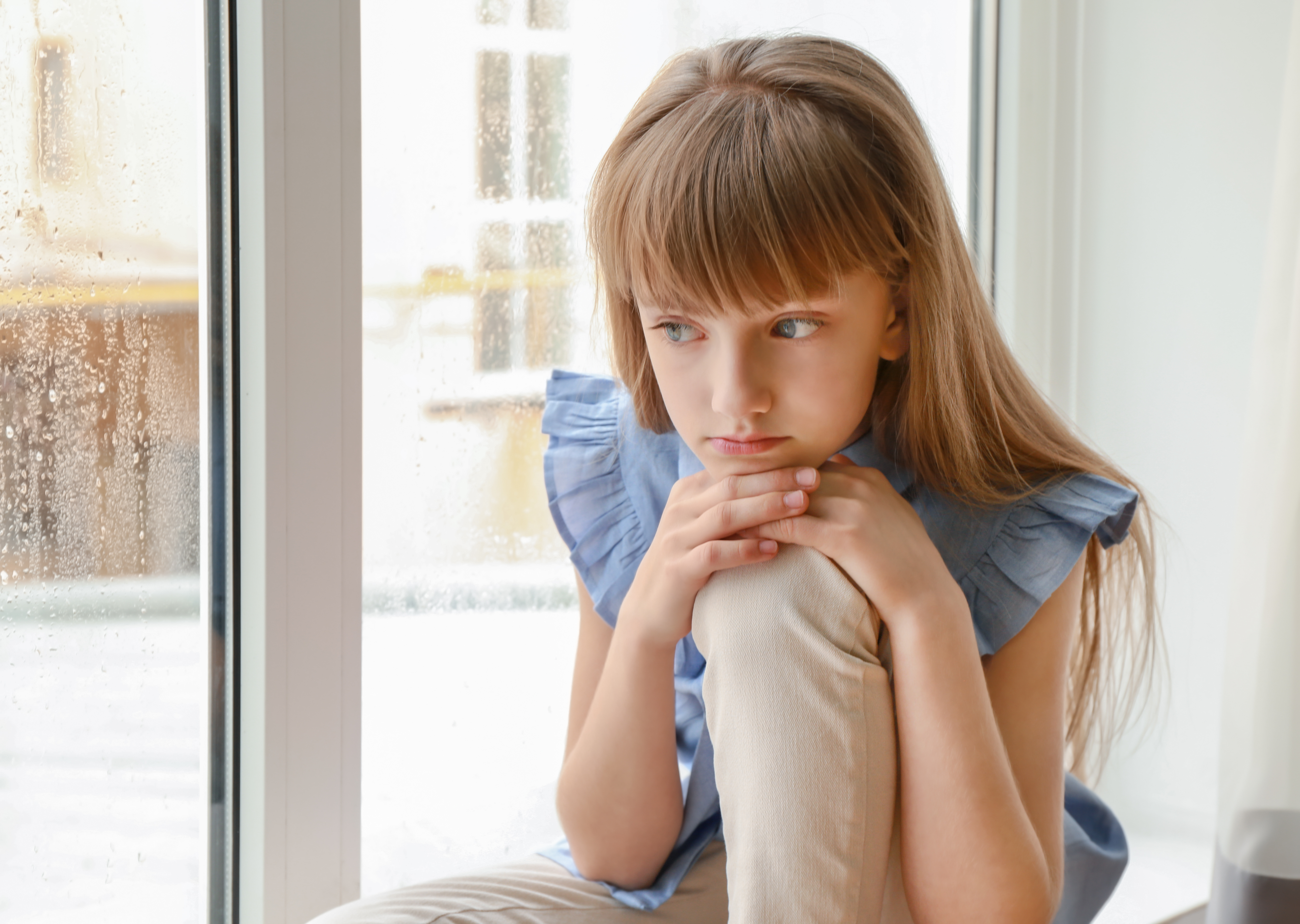 Little girl sulking by the window | Source: Shutterstock
