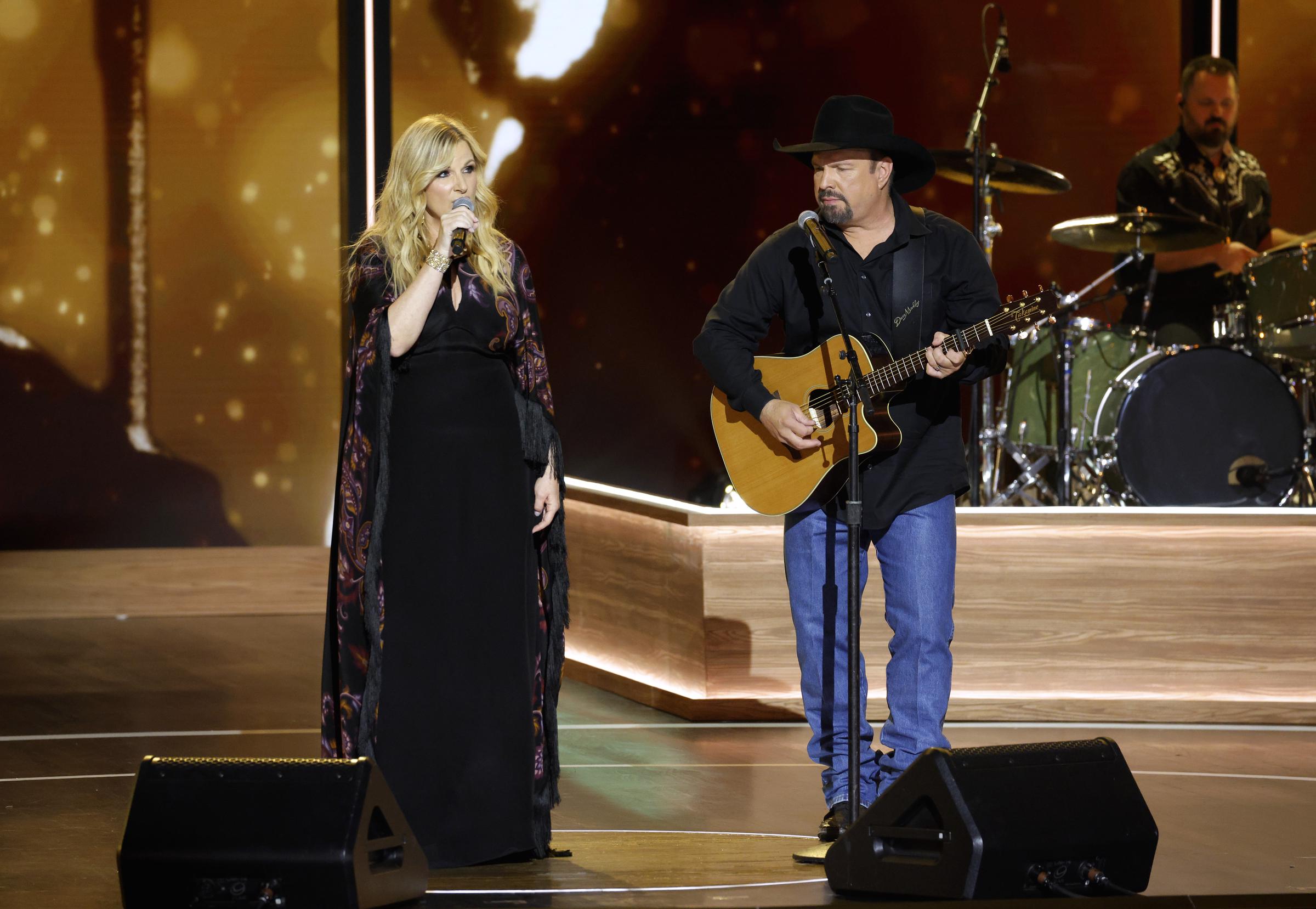 Trisha Yearwood singing while Garth Brooks strums his guitar. | Source: Getty Images