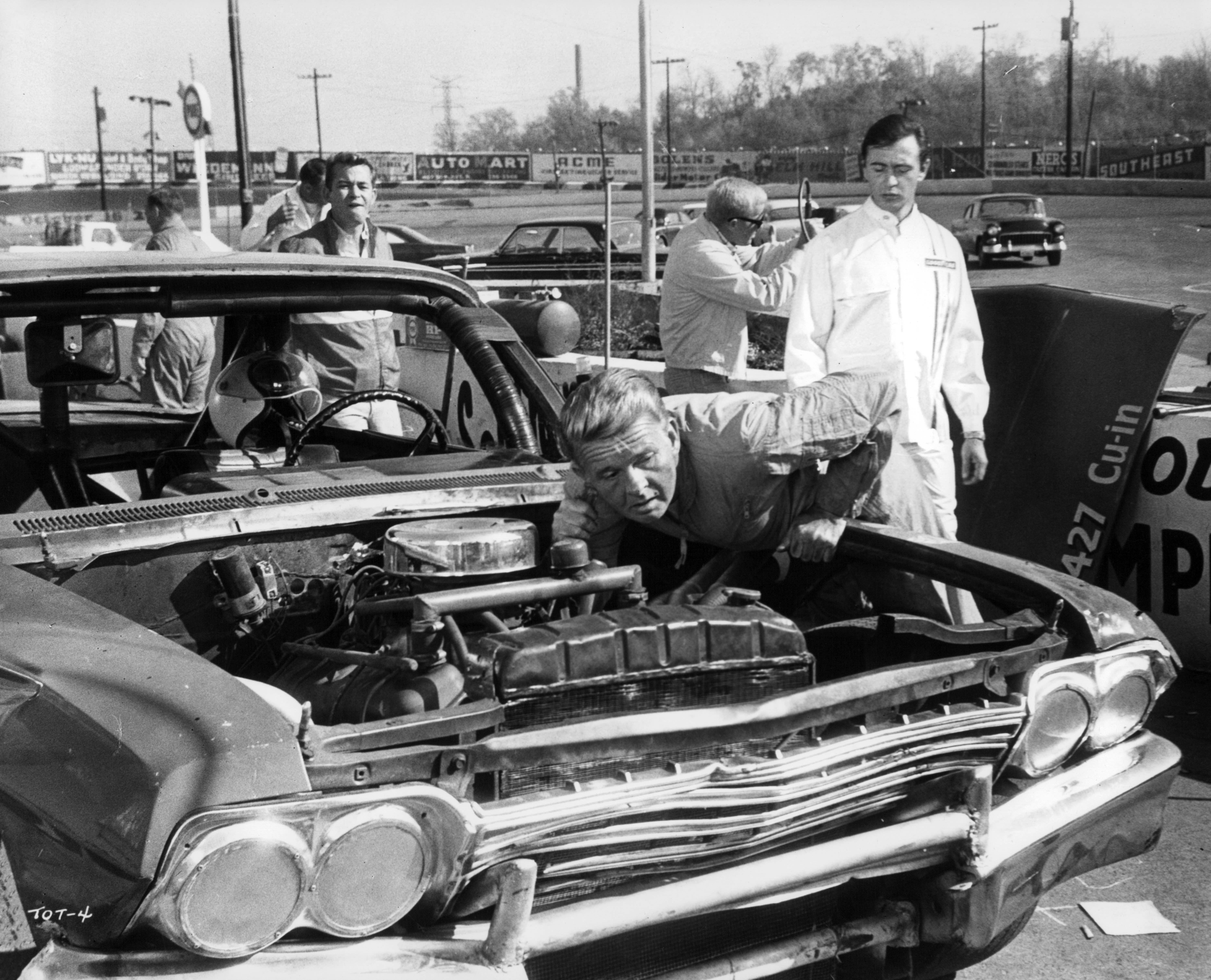 James Dobson inspects a car while Tommy Kirk watches in a scene from the film "Track of Thunder" in 1967 | Photo: United Artists/Getty Images