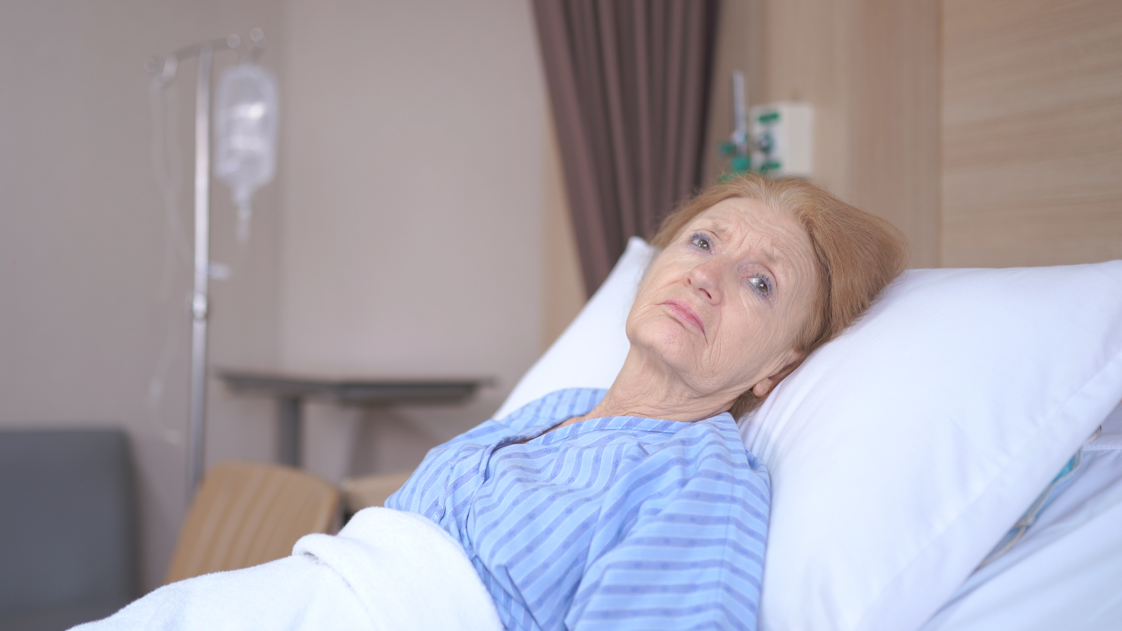 An unhappy senior woman in a hospital bed | Source: Shutterstock