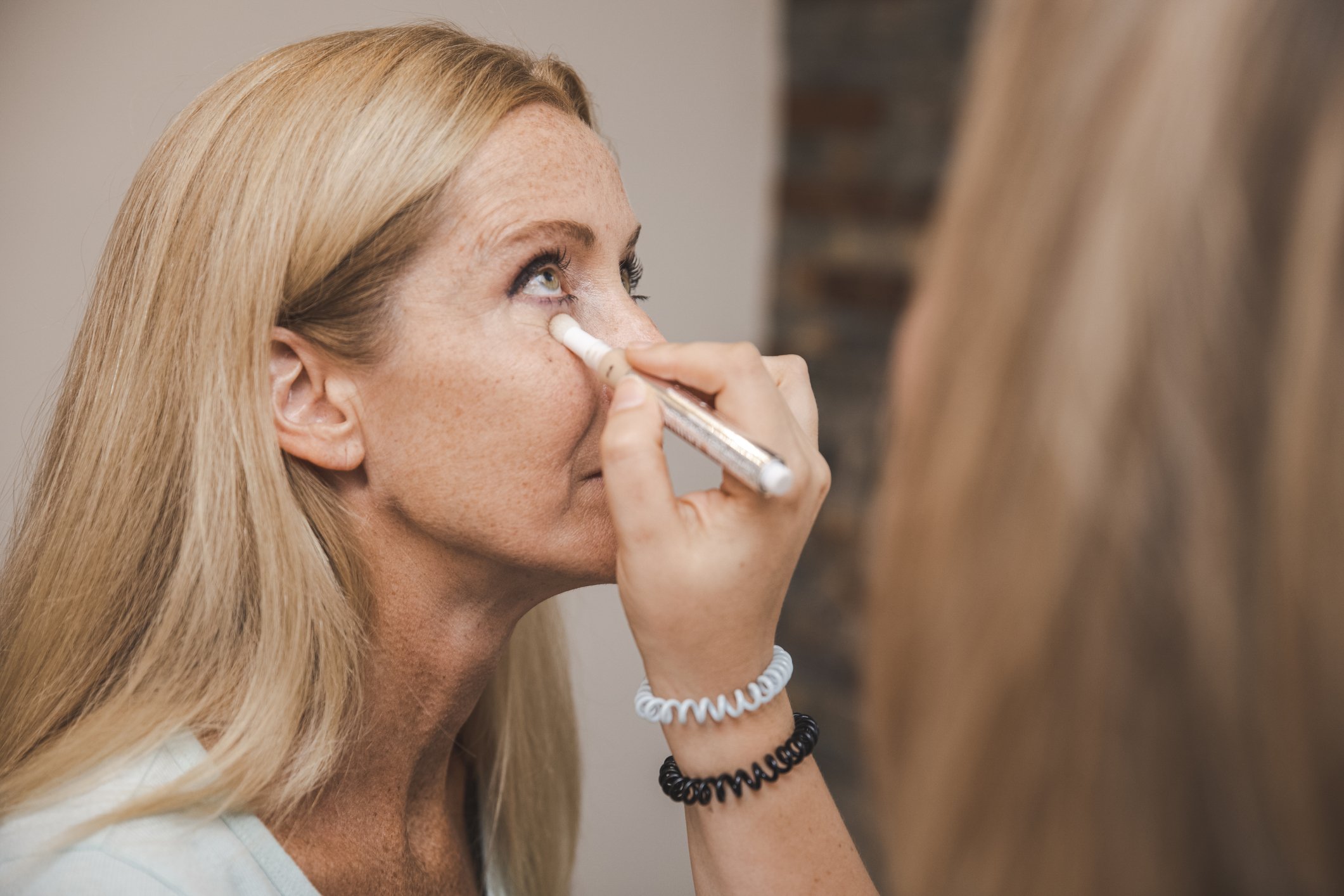Femme utilise un bâton d'anticerne pour couvrir ses cernes. | Photo : Getty Images