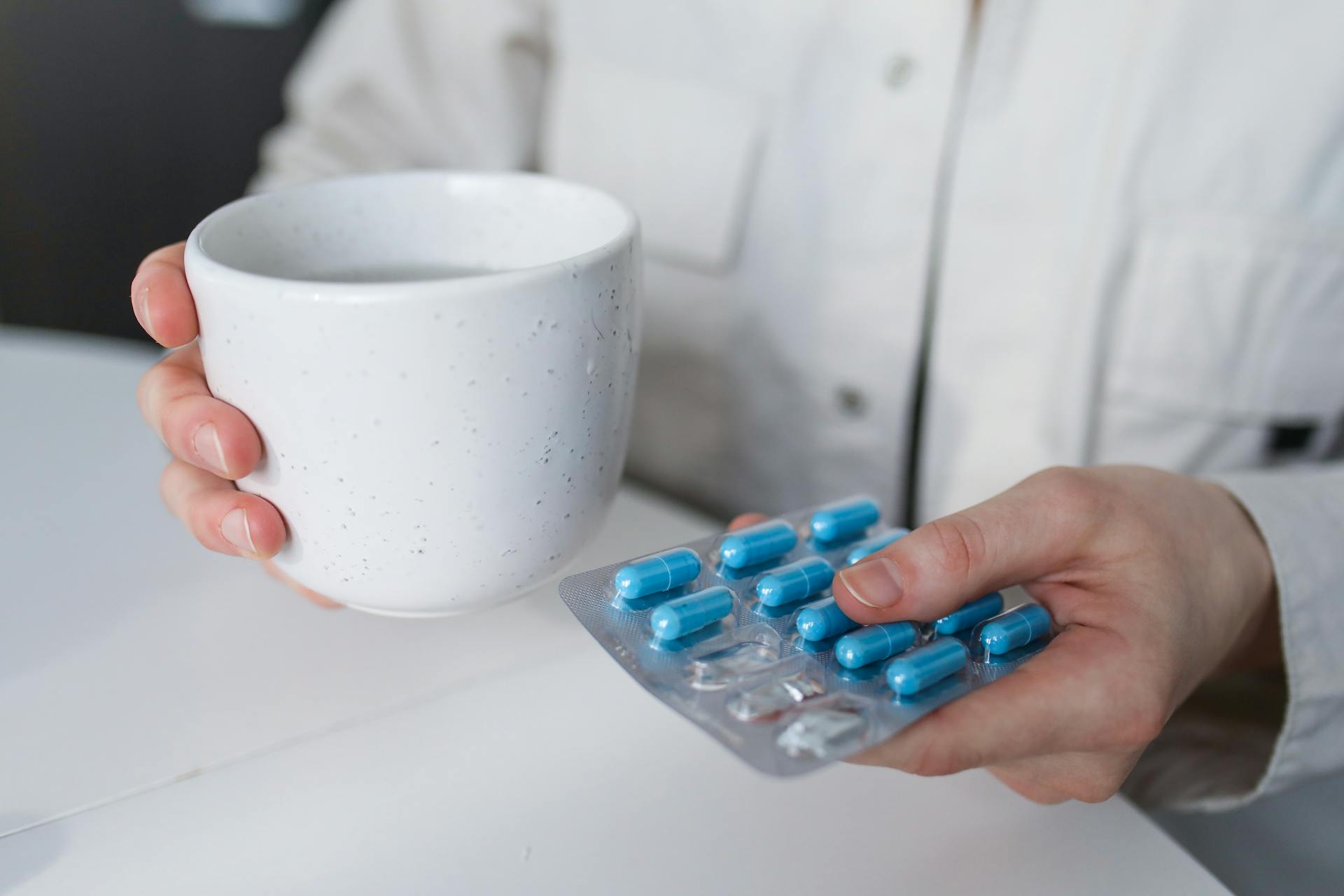 A person holding medicines and a cup of water | Source: Pexels