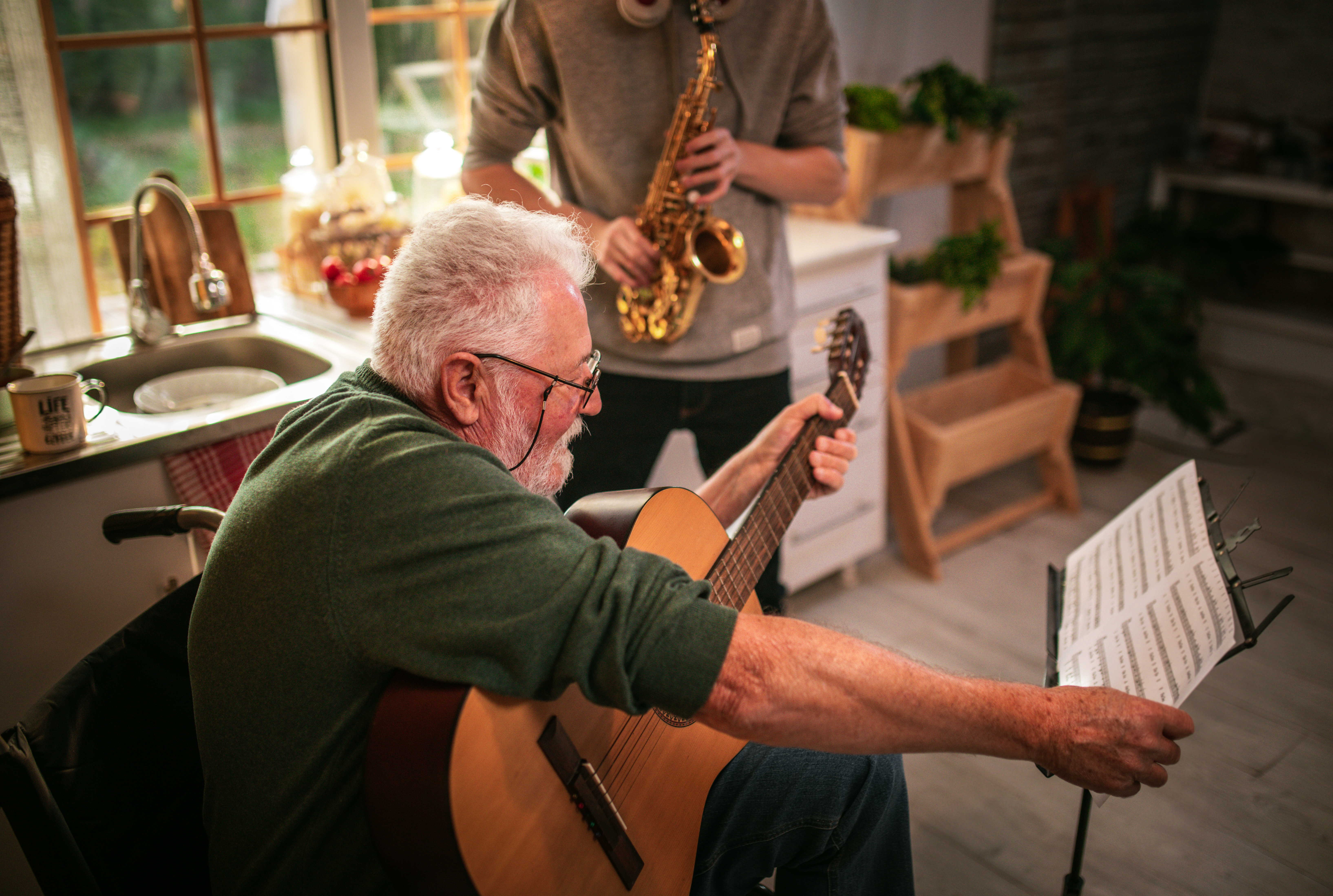 Happy senior man and grandson having fun while playing saxophone and guitar at home. | Source: Getty Images