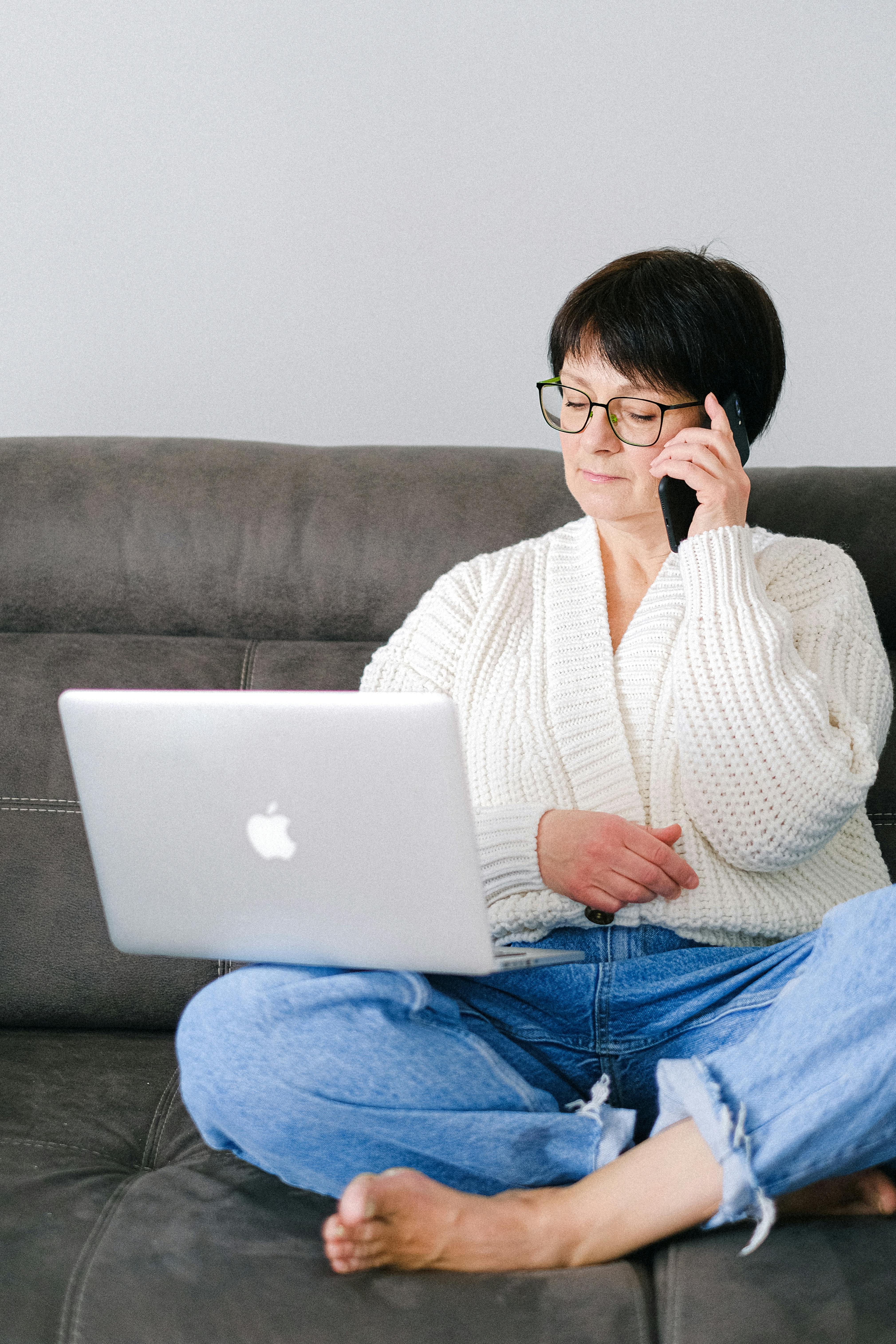 An elderly woman sitting comfortably at home with her gadgets | Source: Pexels