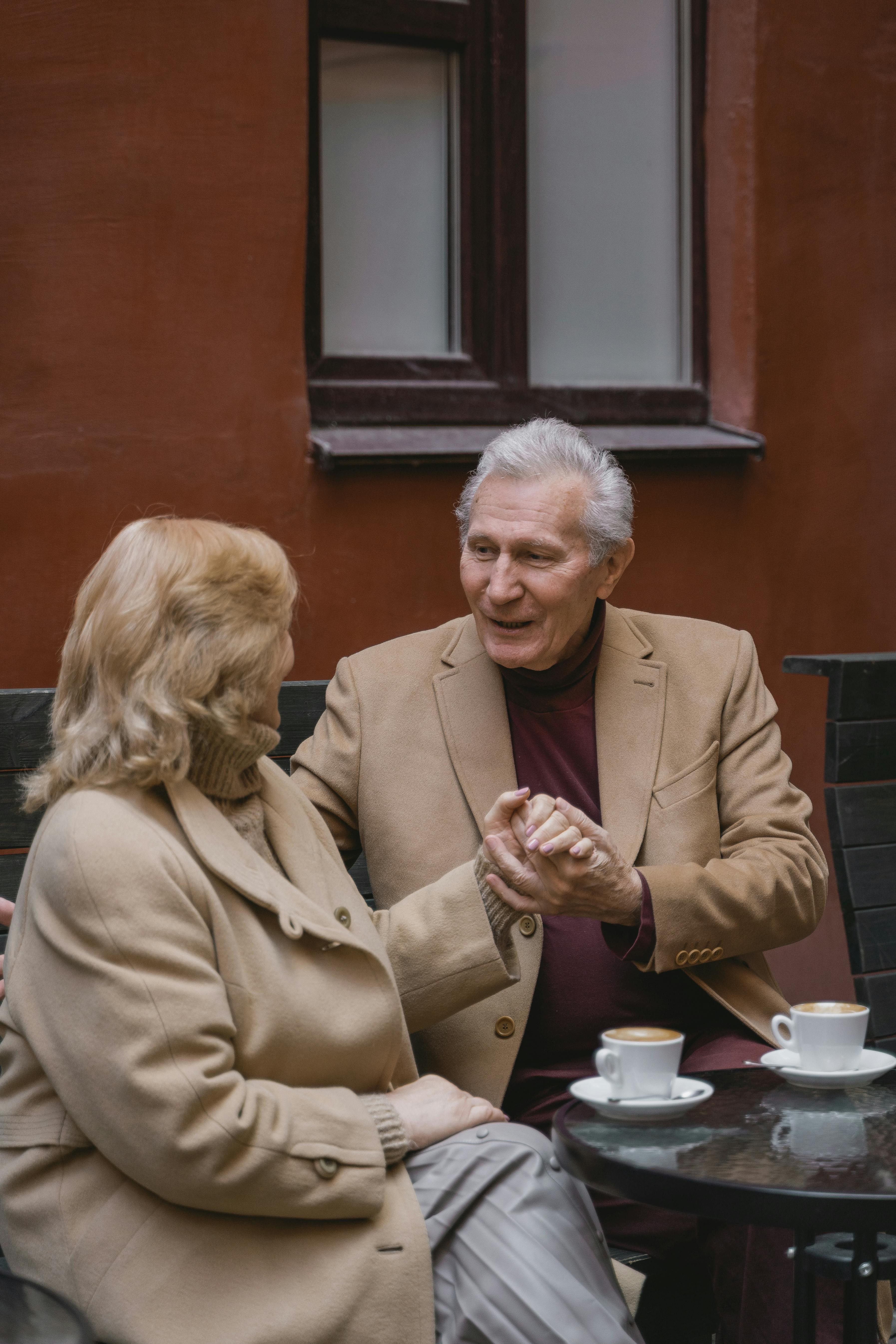 Elderly couple holding hands while having coffee together | Source: Pexels