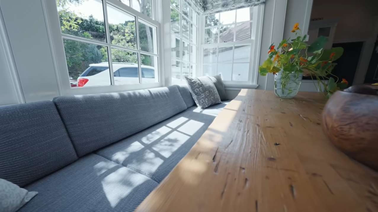 It features a custom booth setup, vibrant drapery, and large windows that flood the room with morning light. | Source: YouTube/@Archdigest
