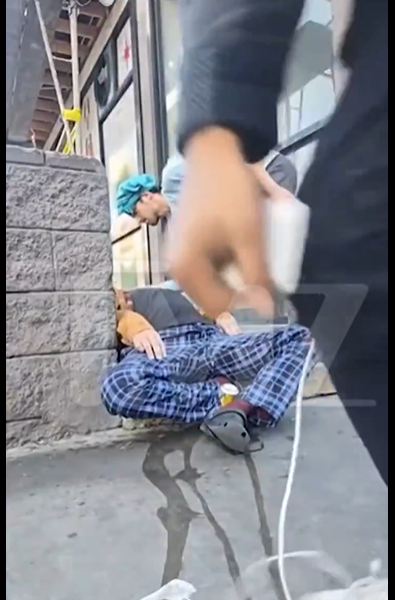 One of Andy Dick's friends still administering the Narcan as the other moves closer to the camera, as seen from a post dated December 10, 2025. | Source: X/TMZ