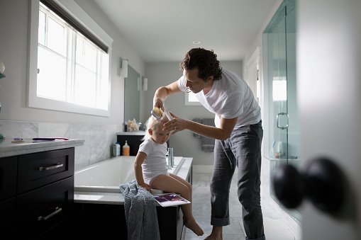 A father brushing his daughter's hair.| Photo: Getty Images.